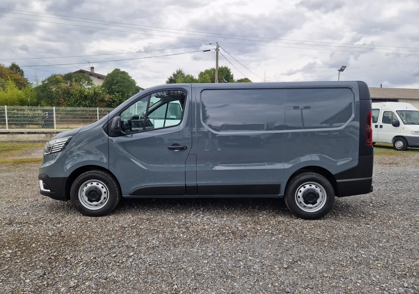 Profil côté gauche d'un Renault Trafic Fourgon gris urbain 2025, avec une silhouette épurée et des jantes acier simples.