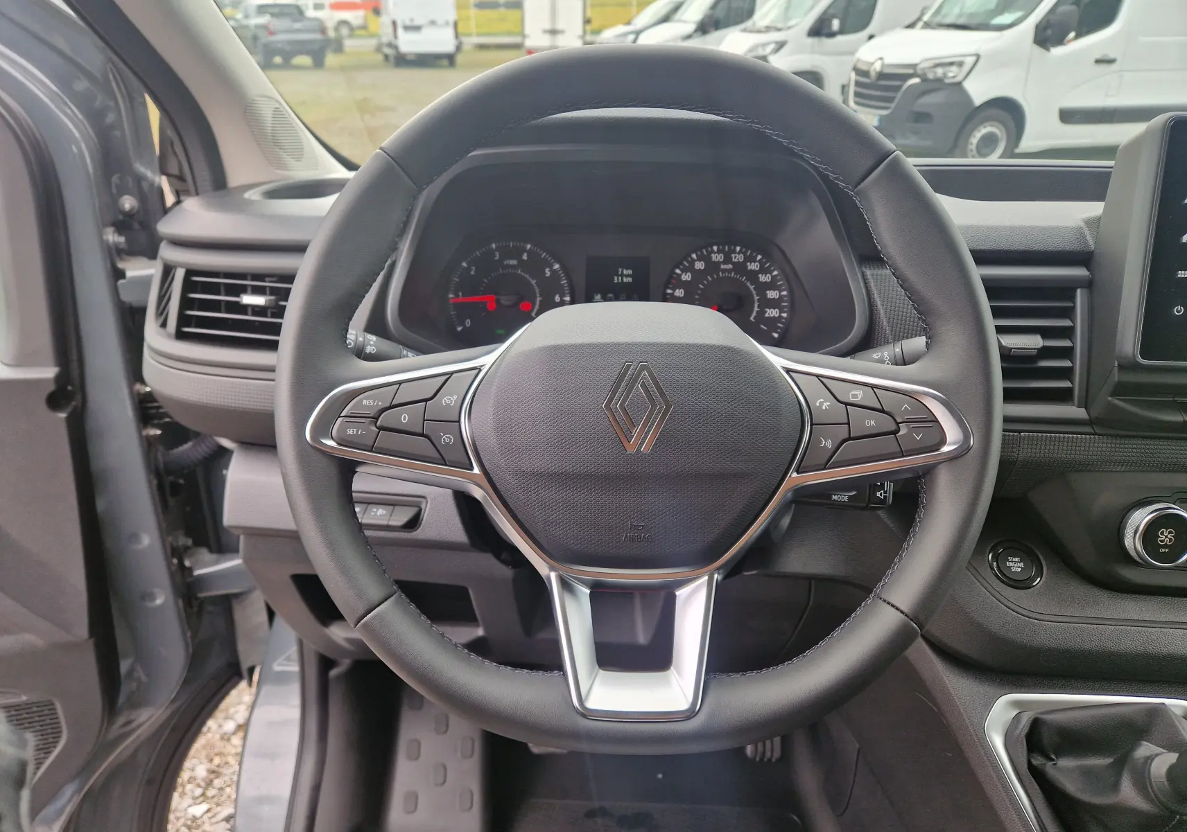 Vue centrée sur le volant noir du Renault Trafic Fourgon gris urbain 2025, avec commandes intégrées et tableau de bord visible.