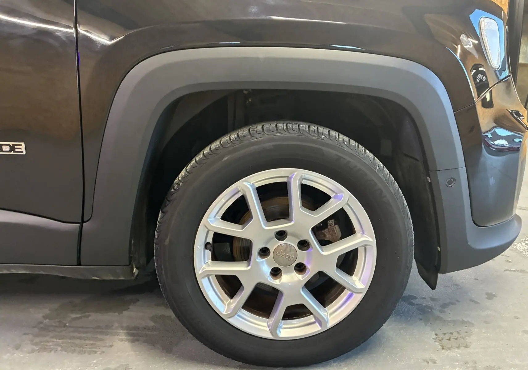 Gros plan sur la roue avant gauche du Jeep Renegade noir, mettant en valeur la jante en alliage et l'aile du véhicule.