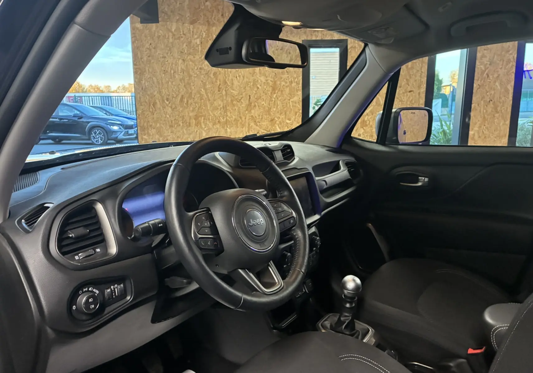 Intérieur noir du Jeep Renegade 2019, vue côté conducteur montrant volant, tableau de bord et levier de vitesses manuel.