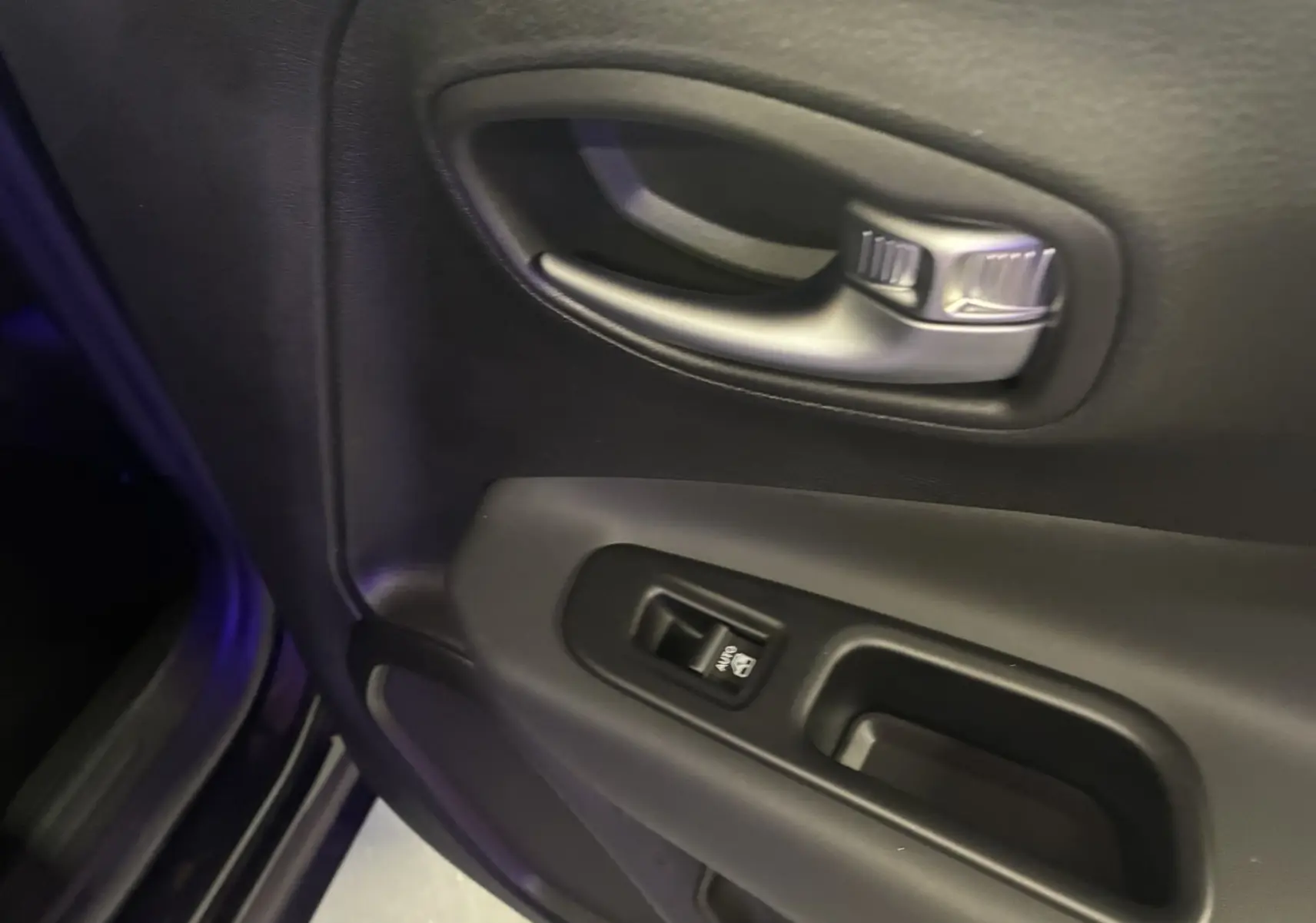 Poignée intérieure et commande de lève-vitre côté conducteur du Jeep Renegade noir, finition Limited 2019.