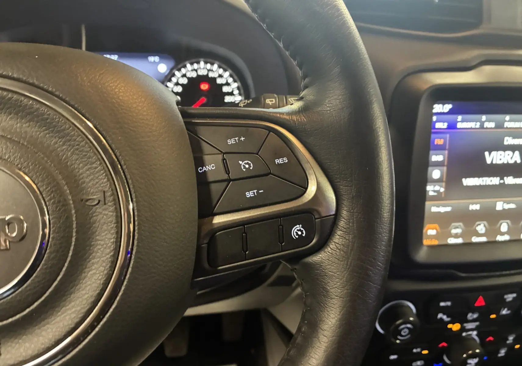 Gros plan sur le volant noir du Jeep Renegade 2019 avec commandes de régulateur de vitesse et tableau de bord lumineux.
