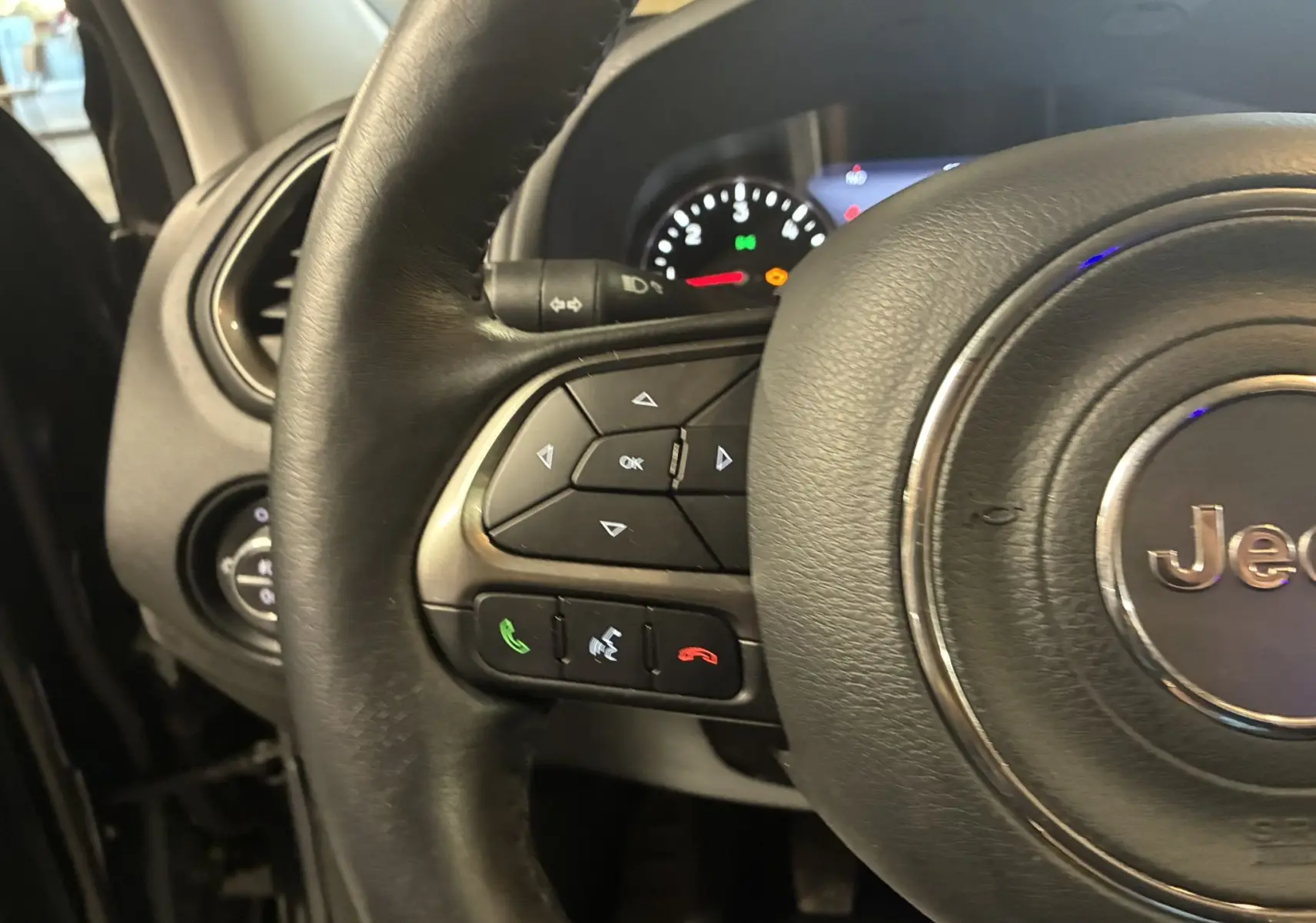 Gros plan sur le volant noir du Jeep Renegade 2019, avec commandes intégrées et tableau de bord en arrière-plan.