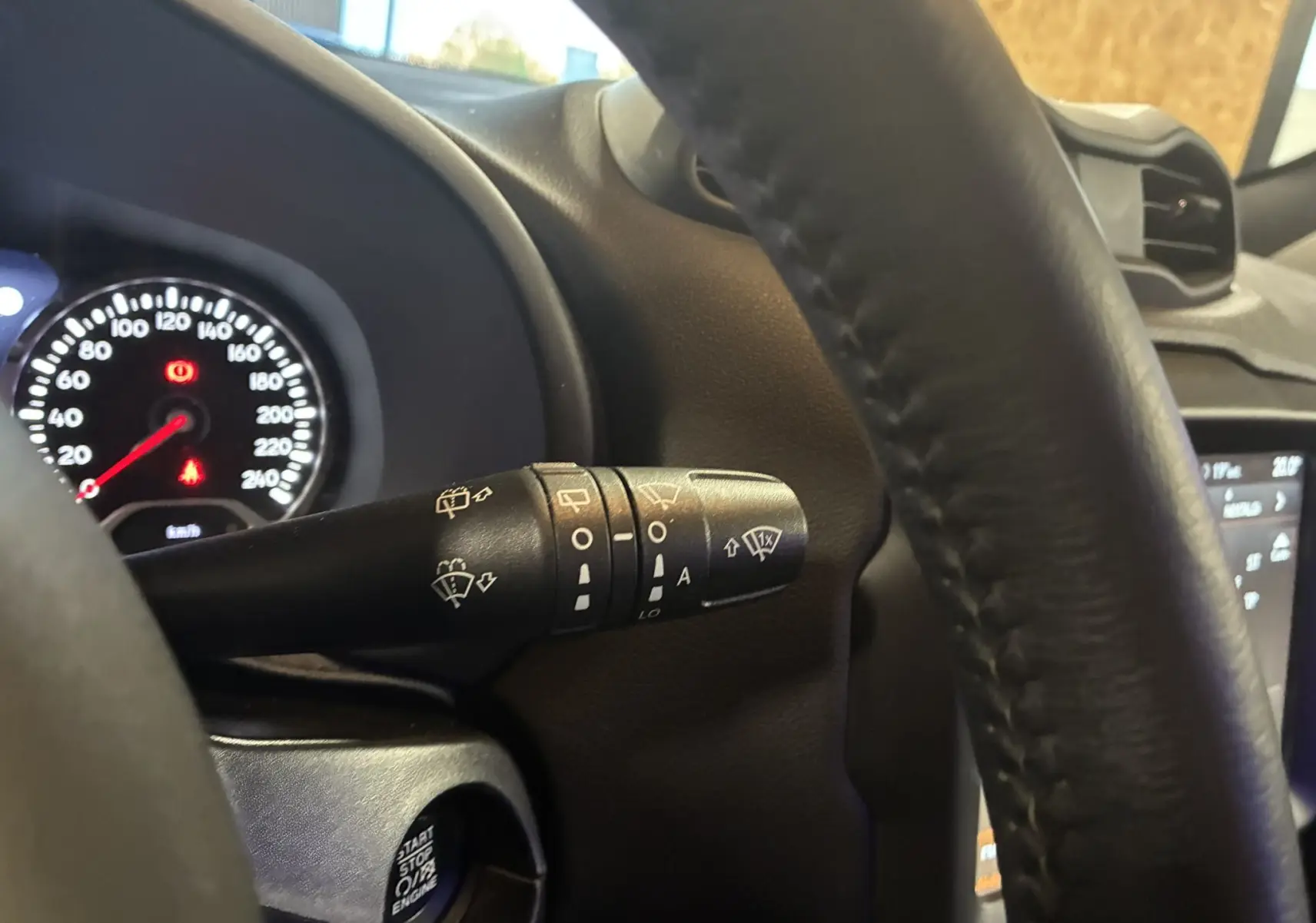 Gros plan sur la manette d'essuie-glace à gauche du volant noir du Jeep Renegade 2019, tableau de bord en arrière-plan.