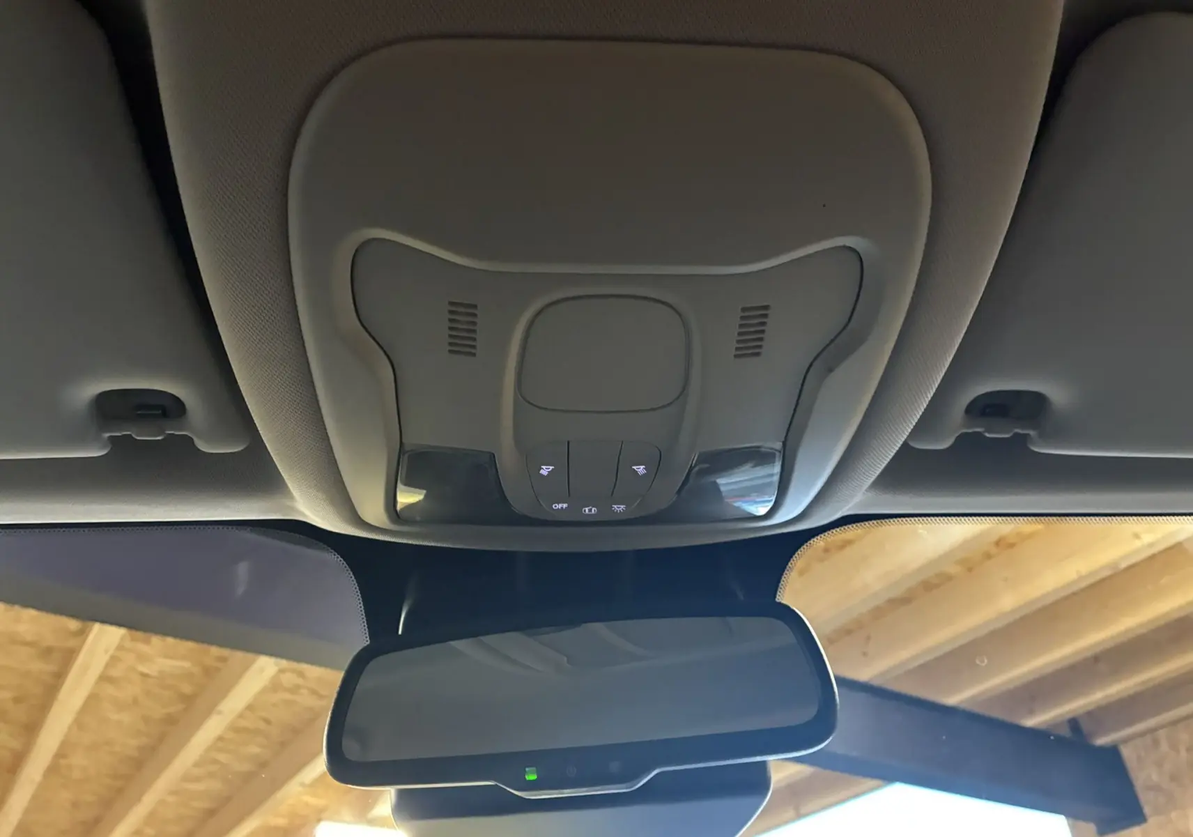 Vue intérieure centrée sur le plafonnier et le rétroviseur d'un Jeep Renegade noir, avec commandes lumineuses visibles.