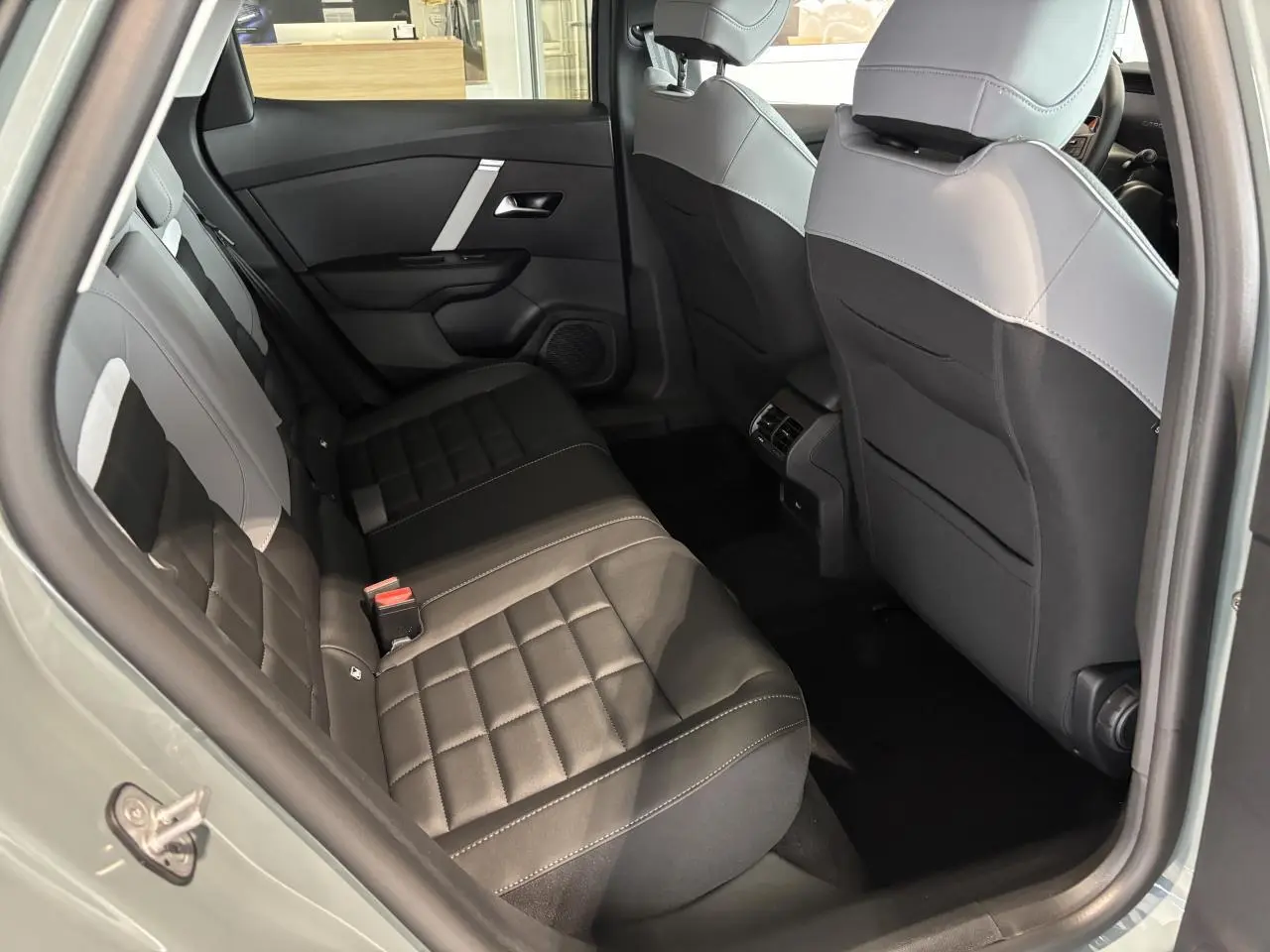 Vue intérieure arrière côté gauche de la Citroën C4 2026 avec sièges tissu noir et gris clair.