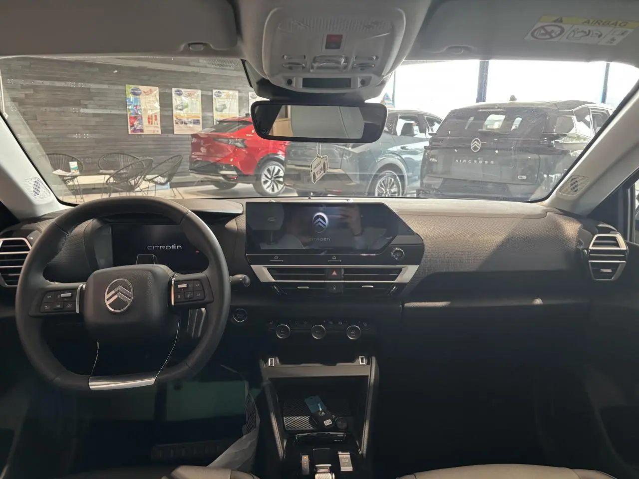 Vue intérieure avant du tableau de bord noir de la Citroën C4 hybride avec écran tactile central et volant multifonctions.
