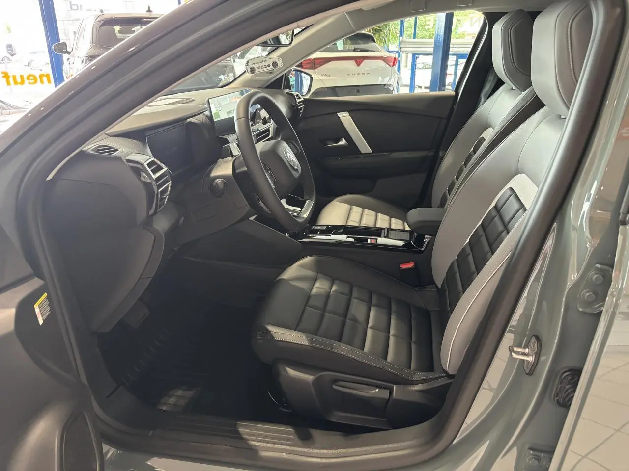 Vue intérieure côté conducteur de la Citroën C4 hybride 2026 en vert Manhattan, sièges Advanced Comfort noirs et gris.