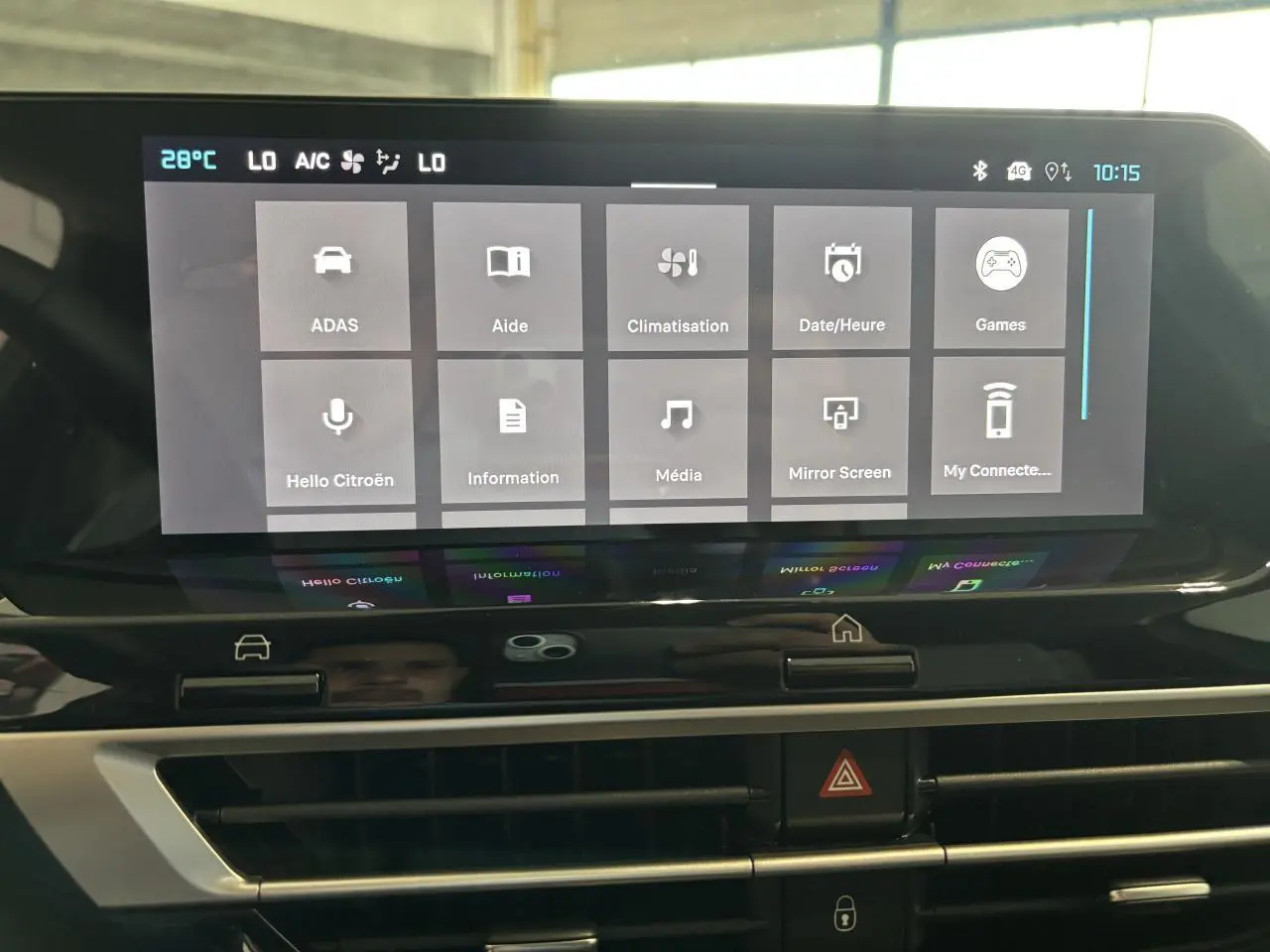 Écran tactile central de la Citroën C4 hybride 2026 montrant le menu principal avec commandes climatisation et aide.