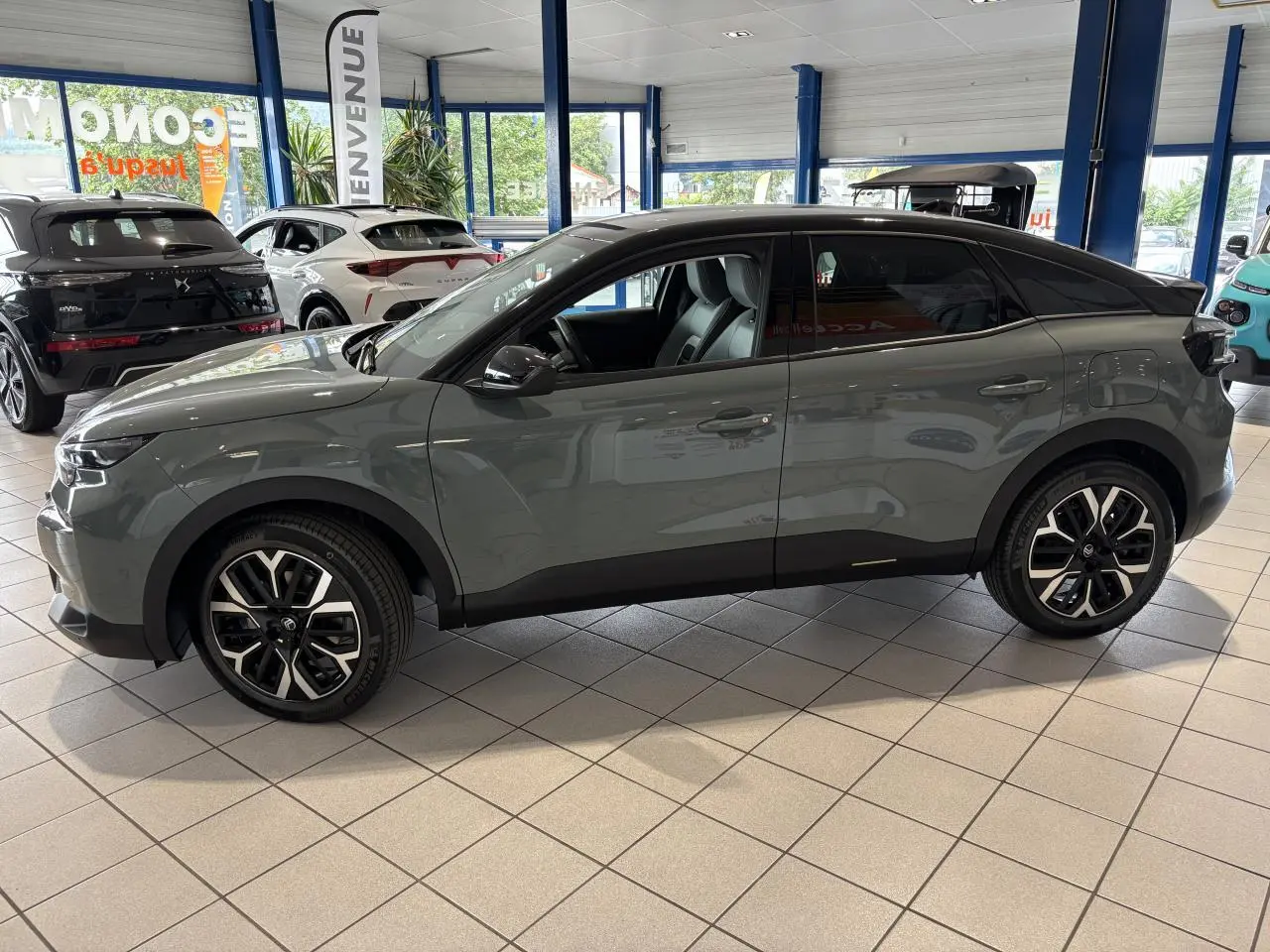 Profil côté gauche d'une Citroën C4 hybride 2026 gris Manhattan avec toit noir et jantes alliage 18 pouces.