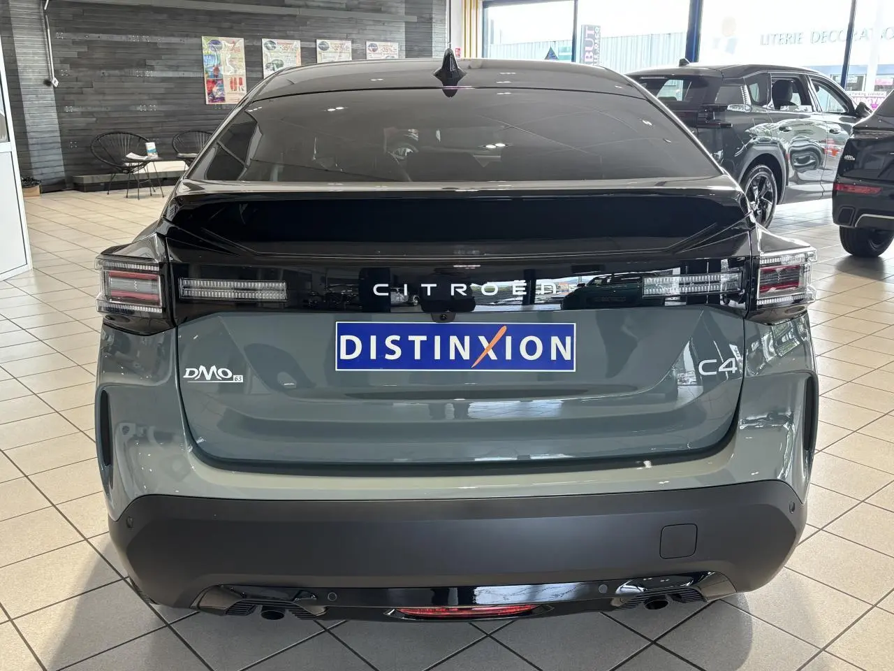 Vue arrière d'une Citroën C4 vert Manhattan avec toit noir Perla Nera en showroom, feux LED et logo distinctif.