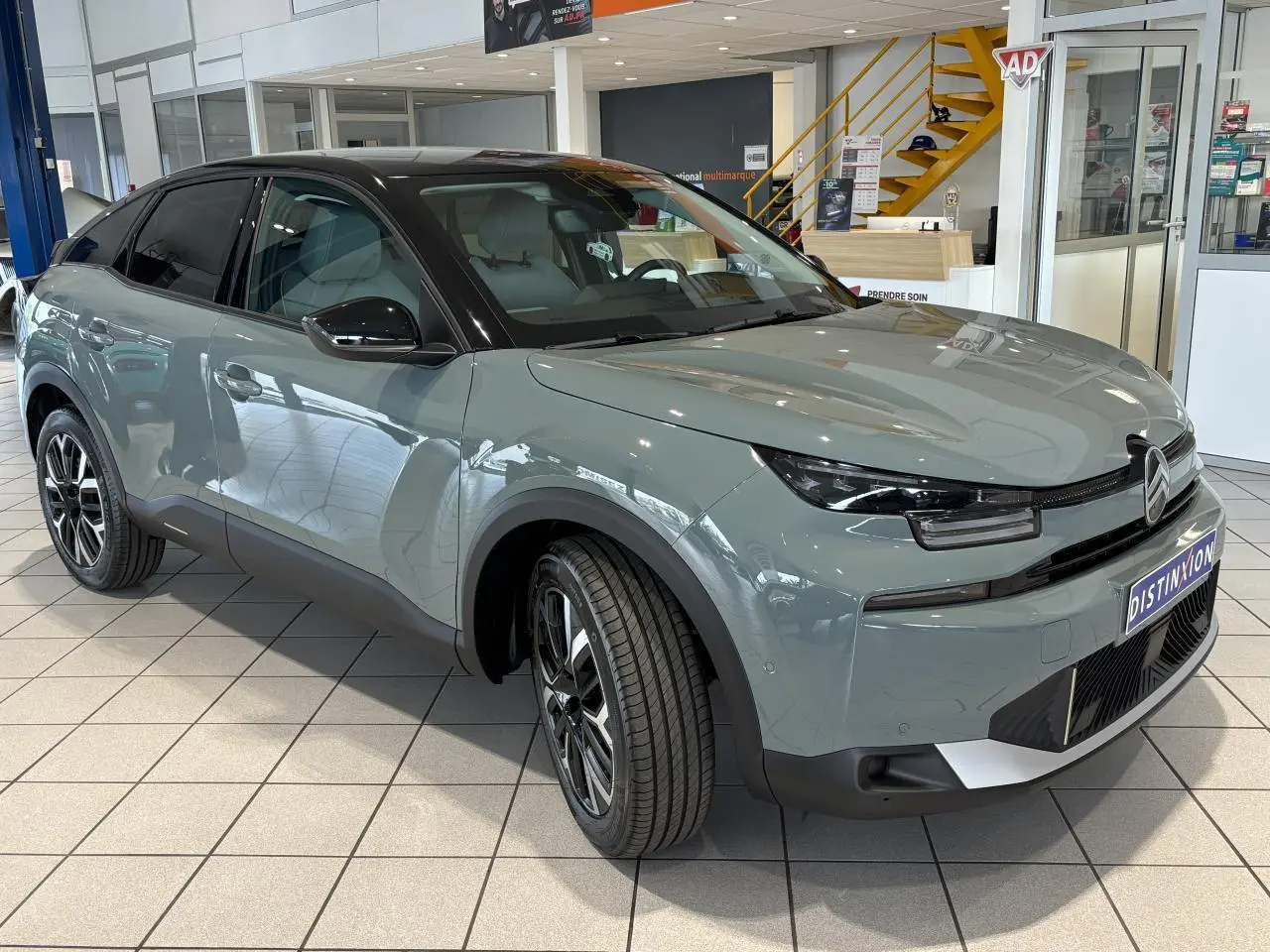 Citroën C4 hybride 2026 vue 3/4 avant en vert Manhattan avec toit noir et jantes alliage 18 pouces.