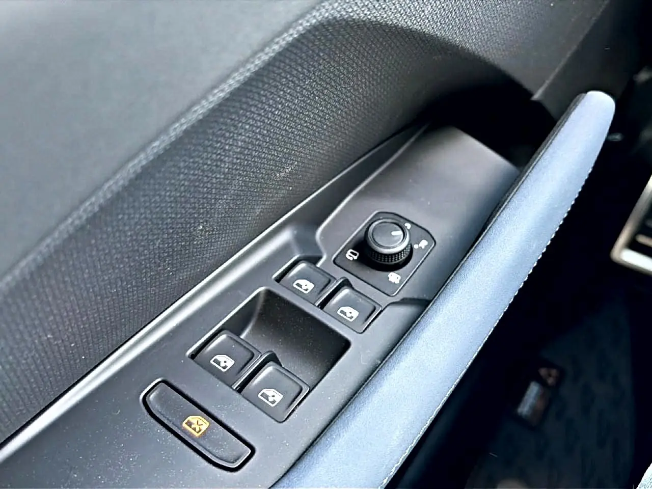 Gros plan sur les commandes de lève-vitres et rétroviseurs côté conducteur avec accoudoir bleu du CUPRA Terramar 2026.
