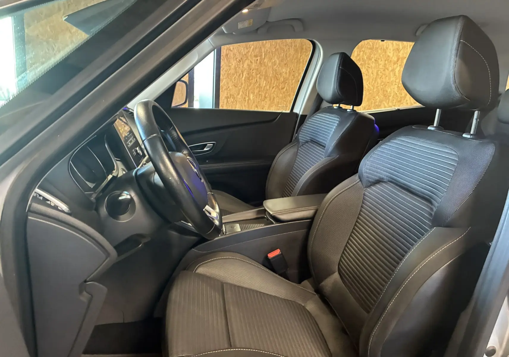 Intérieur noir du Renault Grand Scenic 2017, vue côté gauche sur les sièges avant et le volant cuir.