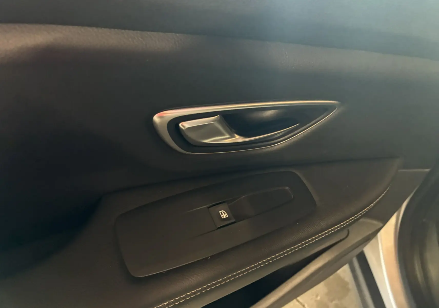 Poignée de porte intérieure côté gauche en cuir noir avec bouton de commande de vitre sur Renault Grand Scenic gris 2017.