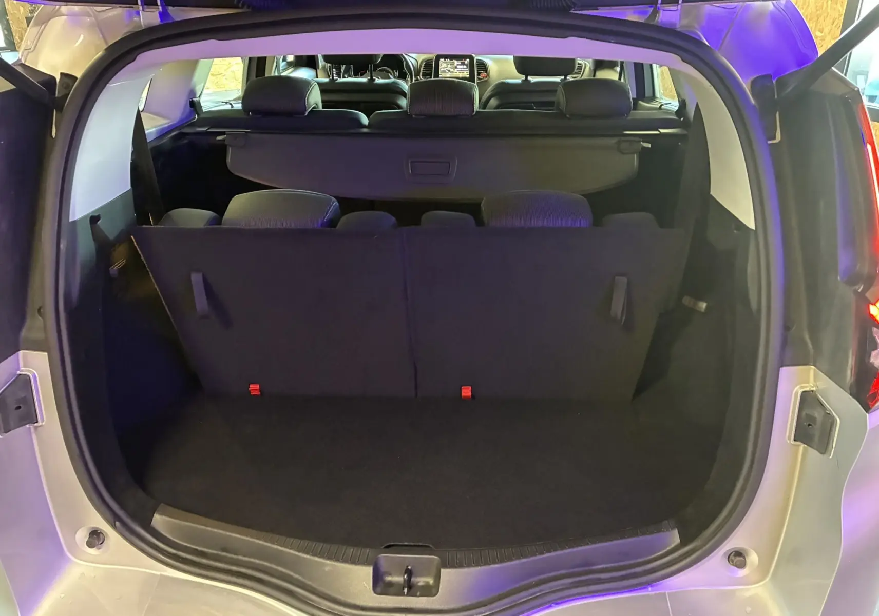 Coffre ouvert vu de l'arrière d'un Renault Grand Scenic gris 2017, montrant la banquette arrière et l'intérieur noir.