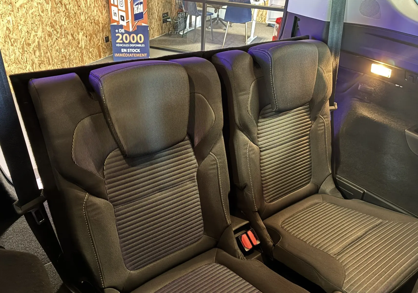 Gros plan sur les sièges arrière noirs en tissu du Renault Grand Scenic gris, version 2017, avec éclairage intérieur allumé.