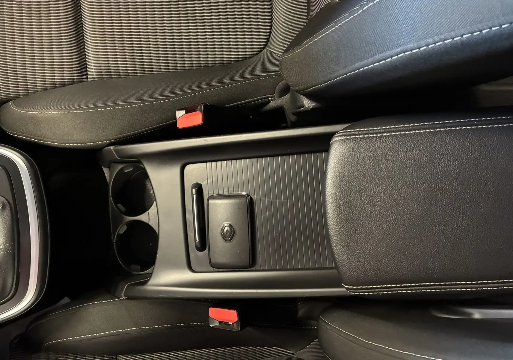 Vue plongeante sur la console centrale noire et les sièges en tissu gris du Renault Grand Scenic 2017.