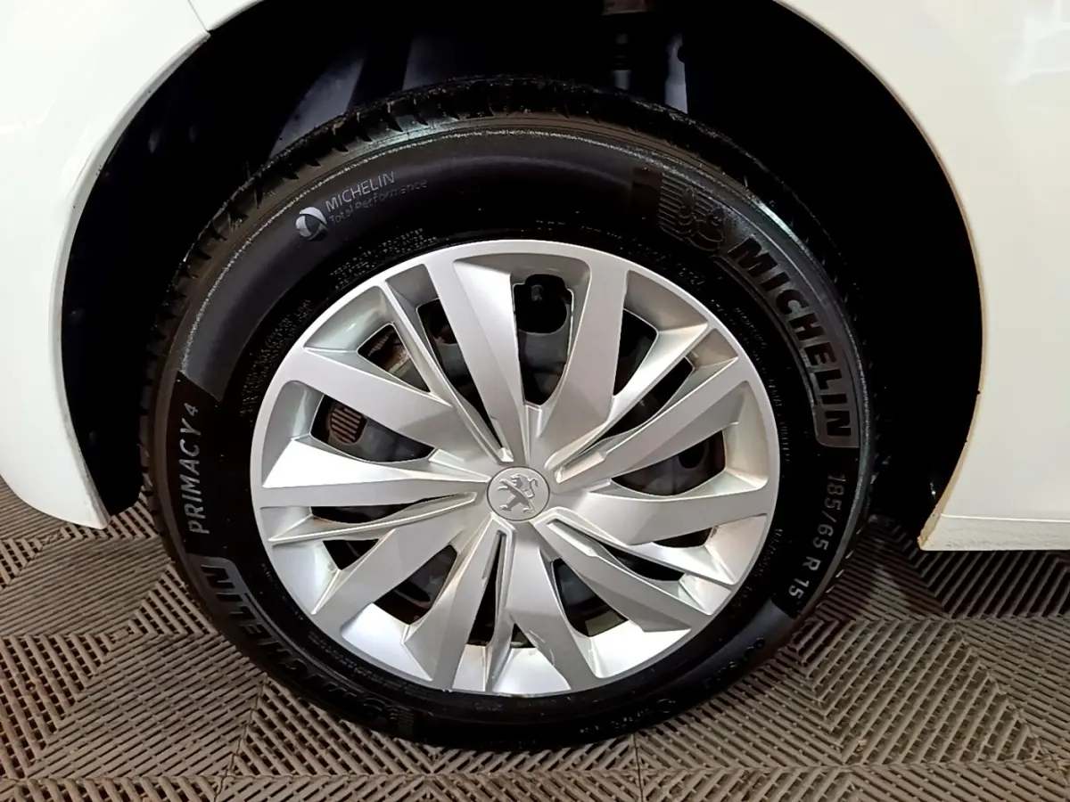Gros plan sur la roue avant droite d'une Peugeot 208 blanche avec jante alliage et pneu Michelin.