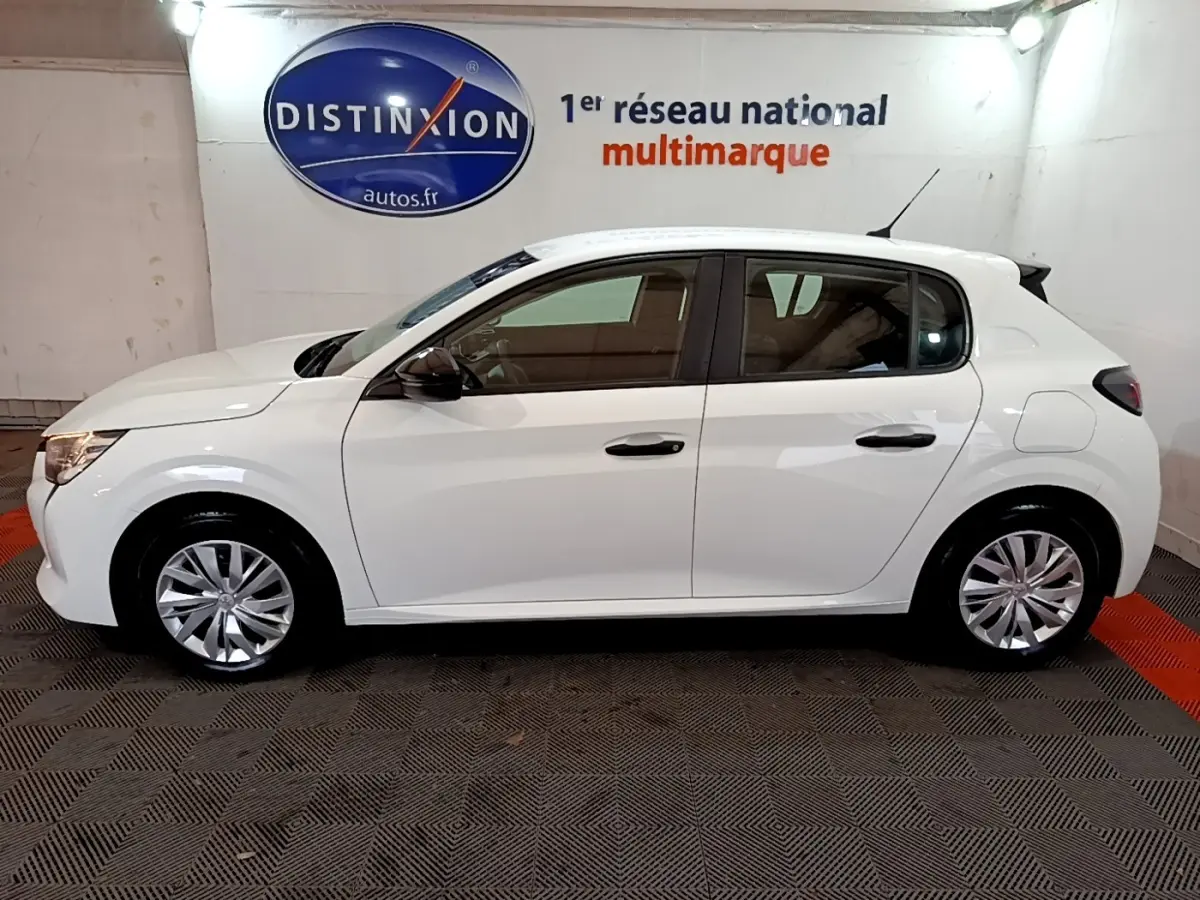 Vue latérale droite d'une Peugeot 208 blanche de 2022, compacte et moderne, stationnée en intérieur sur sol carrelé.