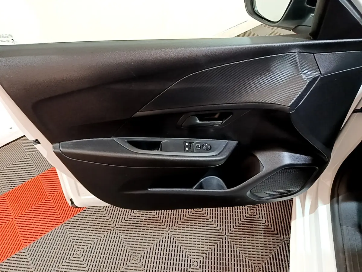 Vue intérieure côté gauche de la porte avant blanche de la Peugeot 208 1.5 BlueHDi avec commandes de vitres et miroir.