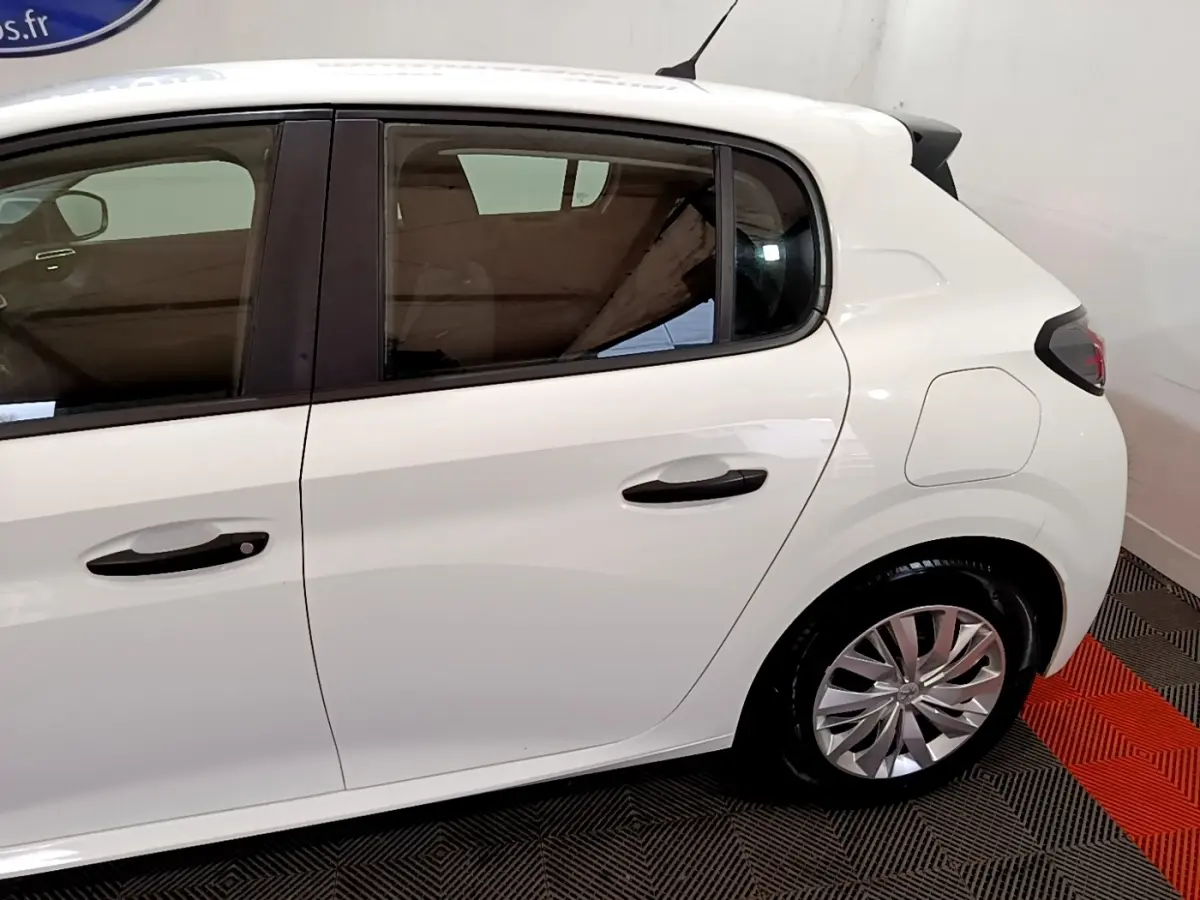 Vue latérale côté droit d'une Peugeot 208 blanche de 2022, mettant en valeur les portes arrière et la roue arrière.