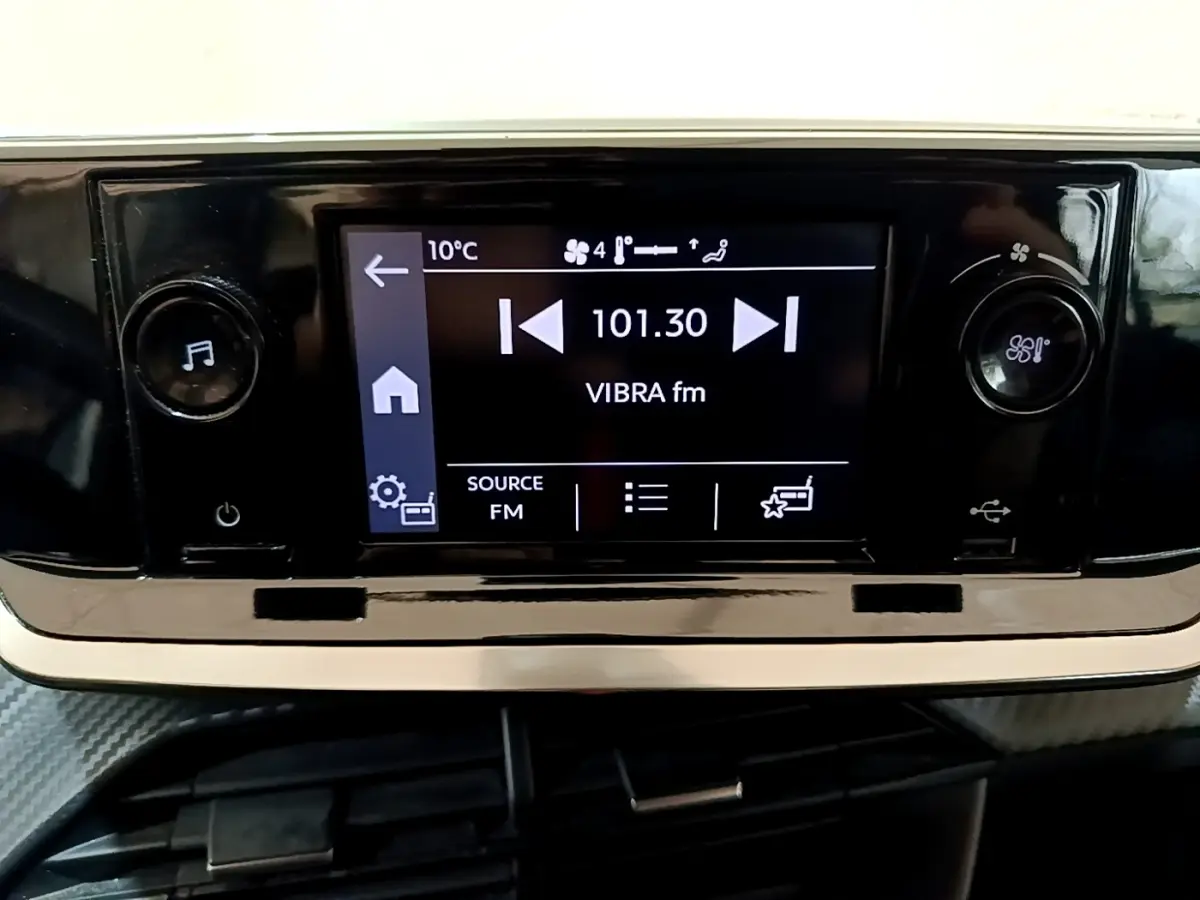 Écran tactile central de la Peugeot 208 blanc montrant la radio FM à 101.30 MHz avec commandes de volume et ventilation.