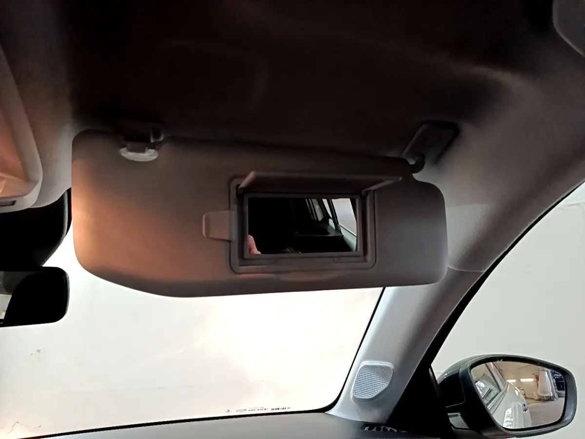 Intérieur de la Peugeot 208 blanc, vue côté passager avec pare-soleil rabattable et miroir de courtoisie ouvert.