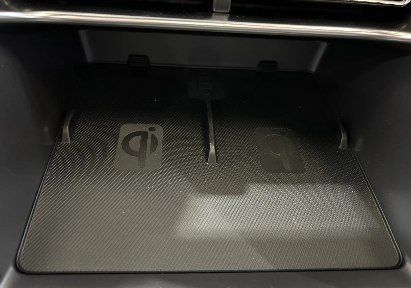 Gros plan sur la zone de recharge sans fil Qi dans l'habitacle du BYD SEAL U, surface noire texturée.