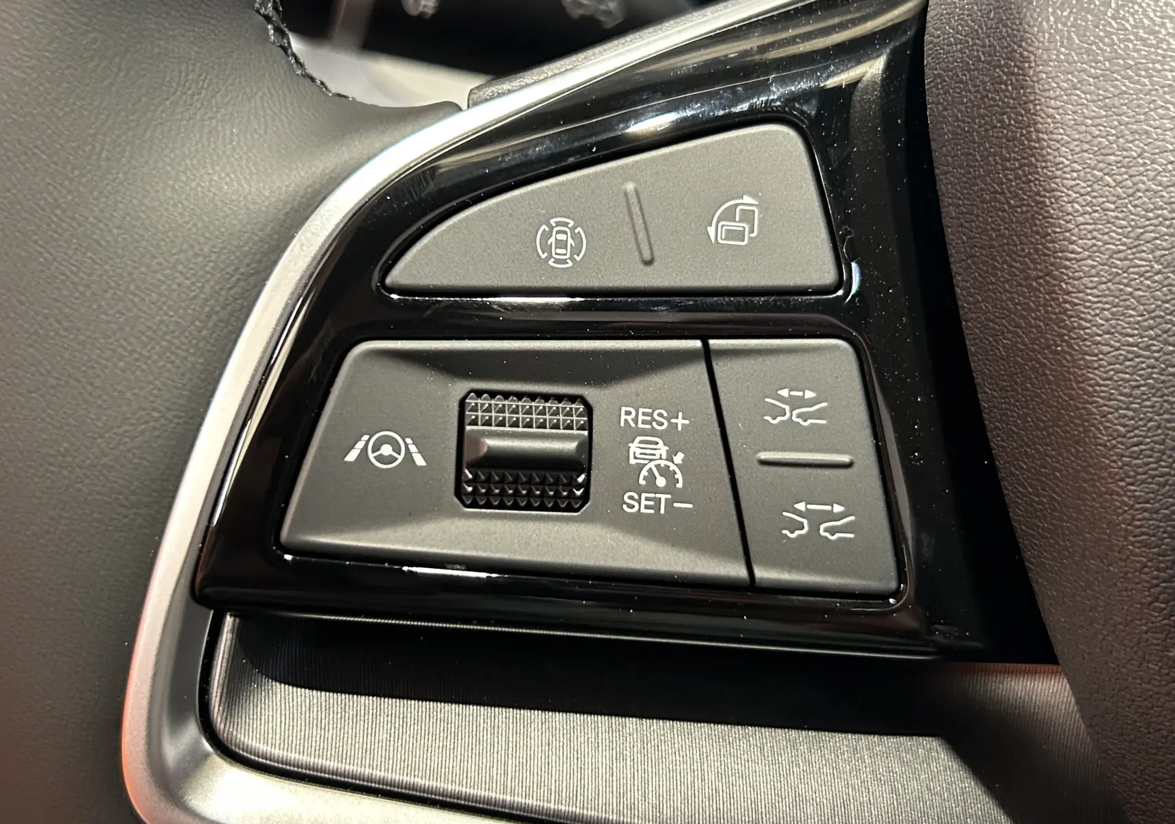 Gros plan sur les commandes noires du volant du BYD SEAL U 2025, avec boutons de régulateur et aides à la conduite.