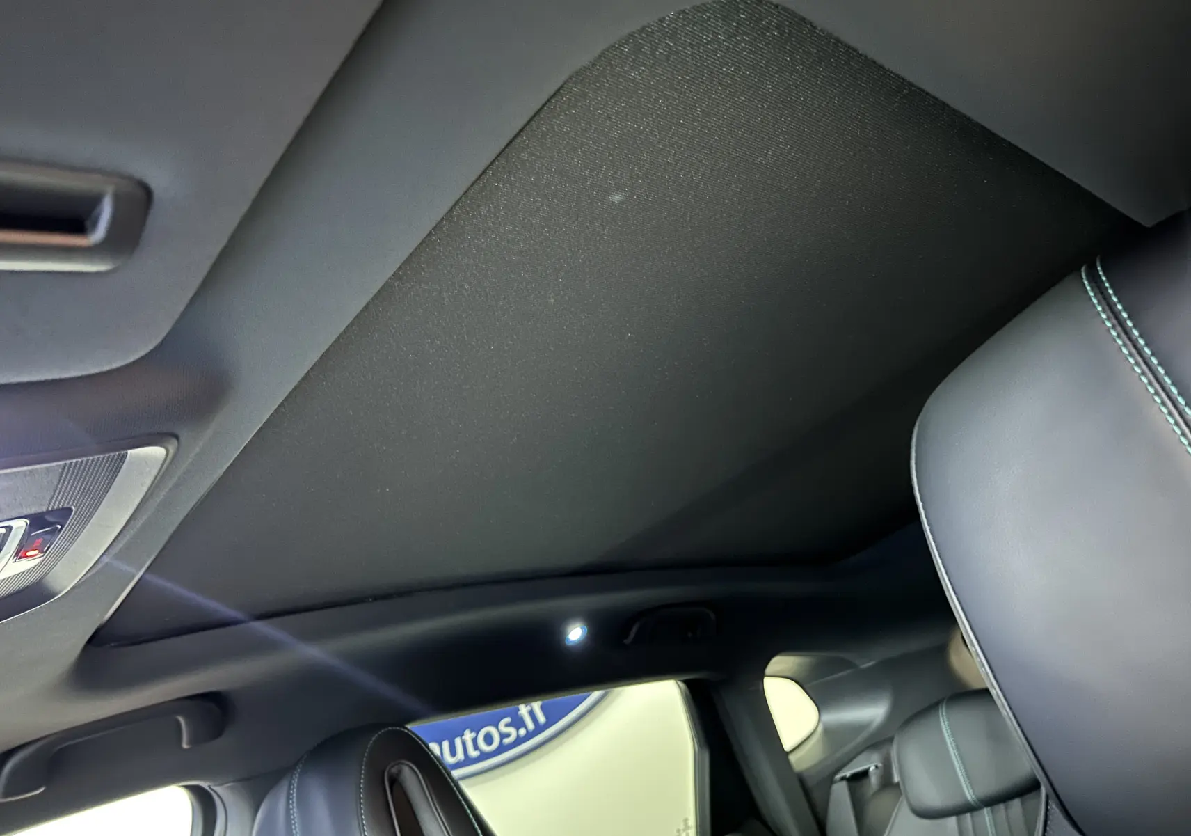Vue intérieure du toit ouvrant fermé et sièges en cuir noir avec surpiqûres bleues du BYD SEAL U 2025.