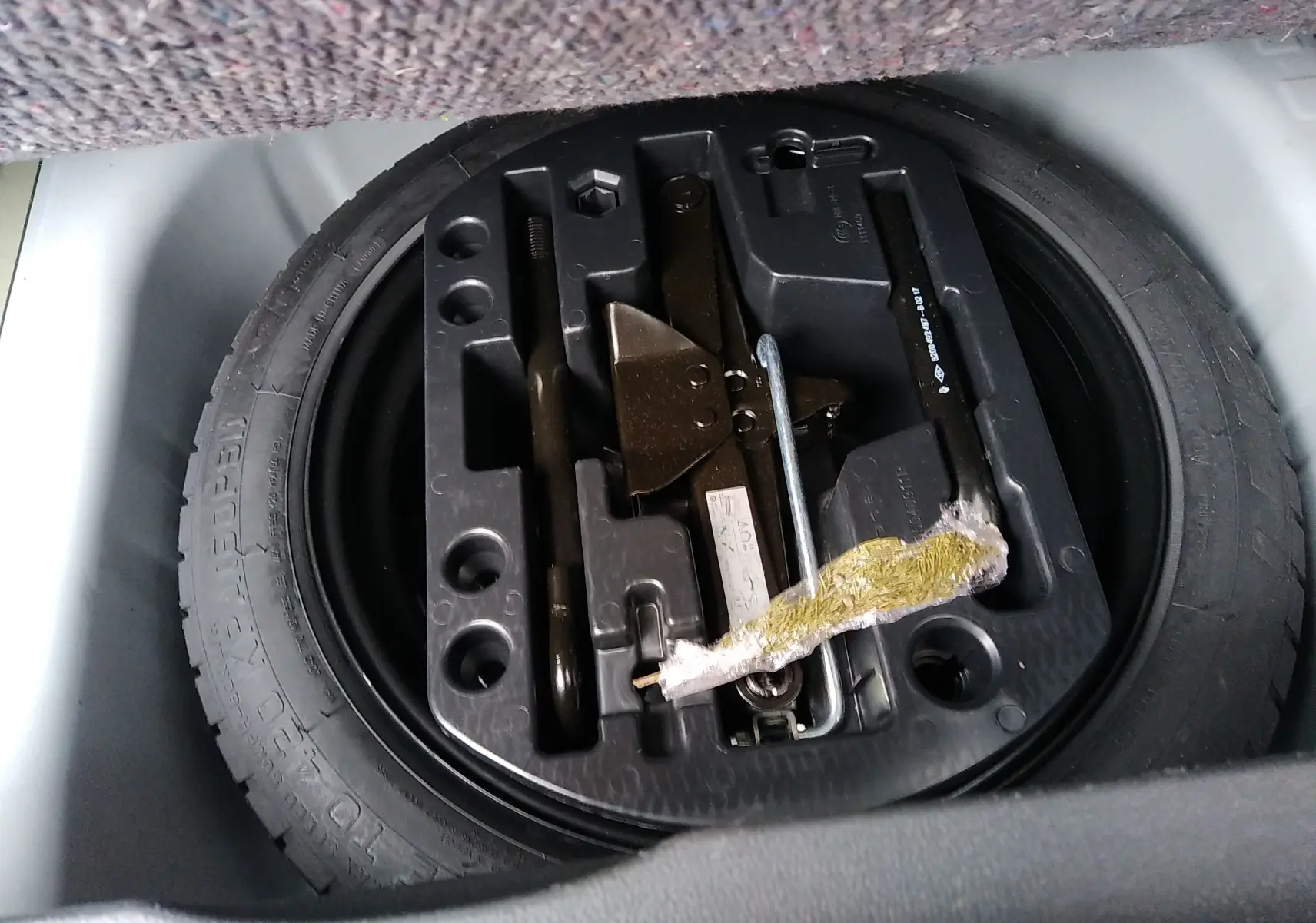 Gros plan sur la roue de secours et le kit d'outils dans le coffre d'un Renault Captur blanc 2017.