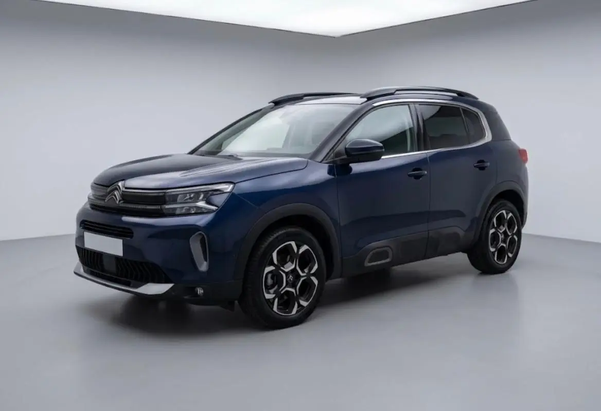 Citroën C5 Aircross hybride bleu foncé vu en 3/4 avant droit, avec jantes distinctives et barres de toit noires.