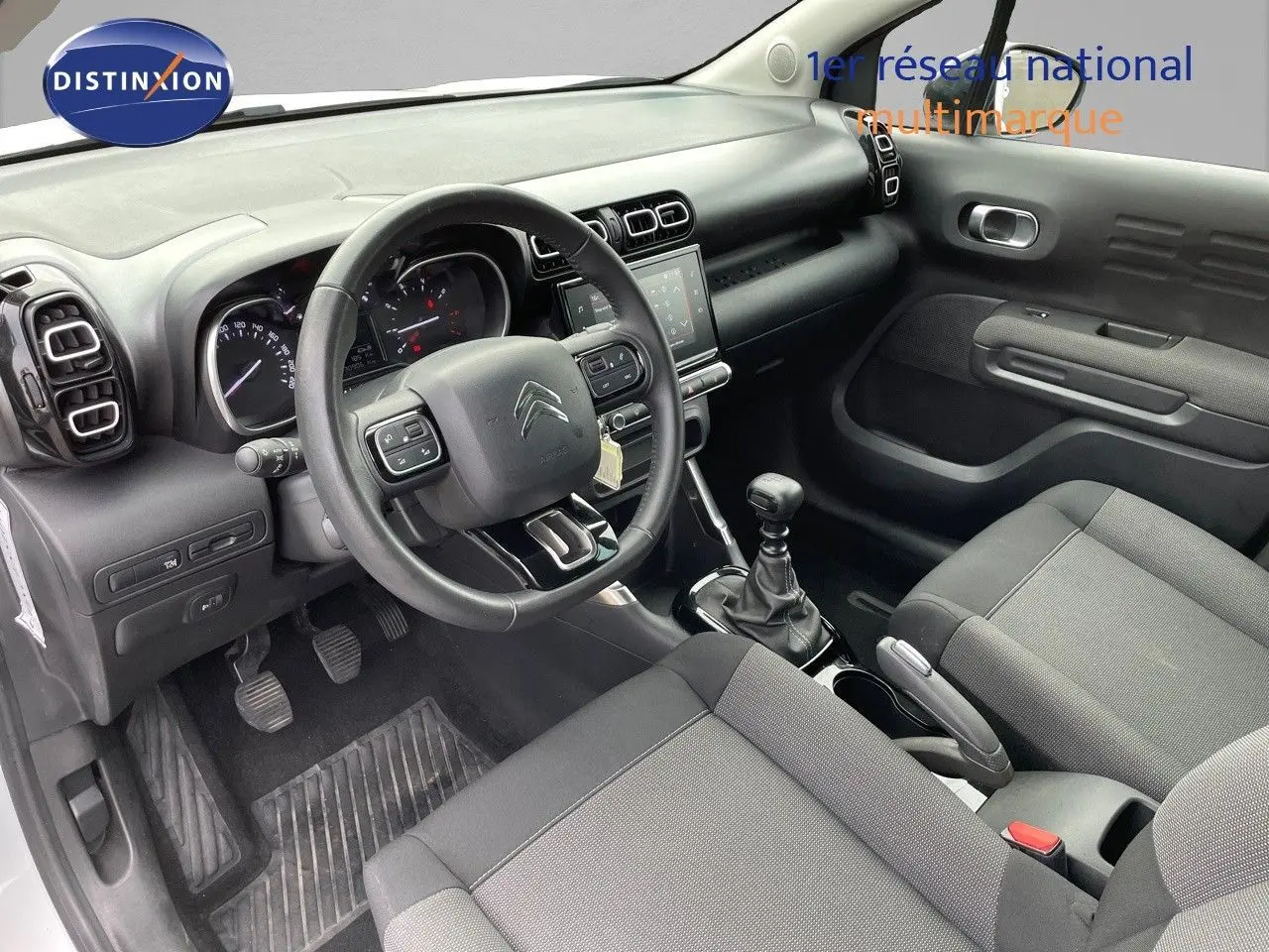 Intérieur du Citroën C3 Aircross 2023 en tissu gris, vue côté conducteur avec volant multifonction et boîte manuelle.