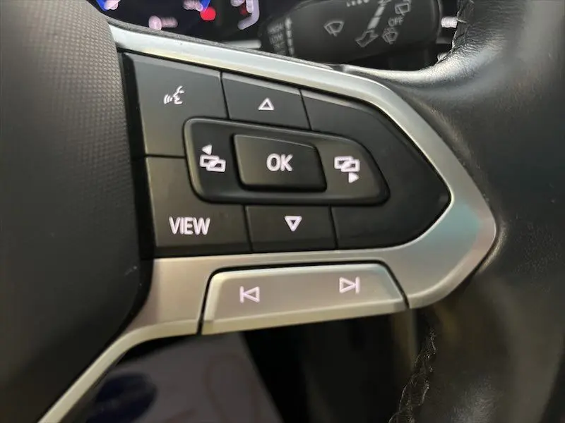 Gros plan sur les commandes au volant noir et argent du Volkswagen T-cross 1.0 TSI 110 DSG Carat 2021, intérieur moderne.