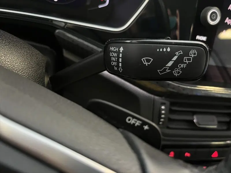 Gros plan sur la commande des essuie-glaces du Volkswagen T-Cross 1.0 TSI 110 DSG Carat, intérieur noir.