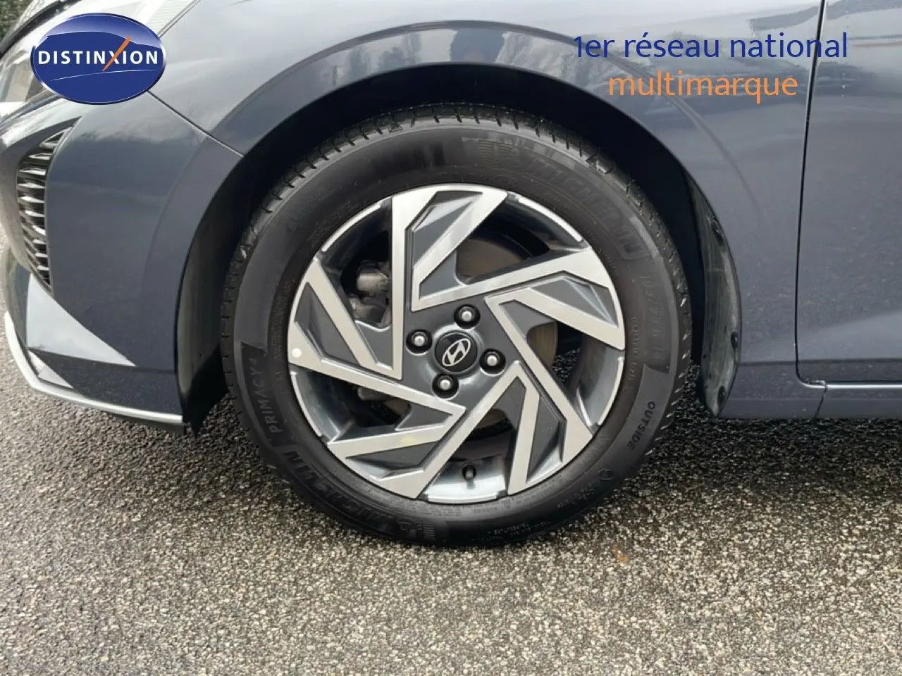 Gros plan sur la roue avant gauche d'une Hyundai i20 gris Aurora Metal avec jante alliage au design géométrique.