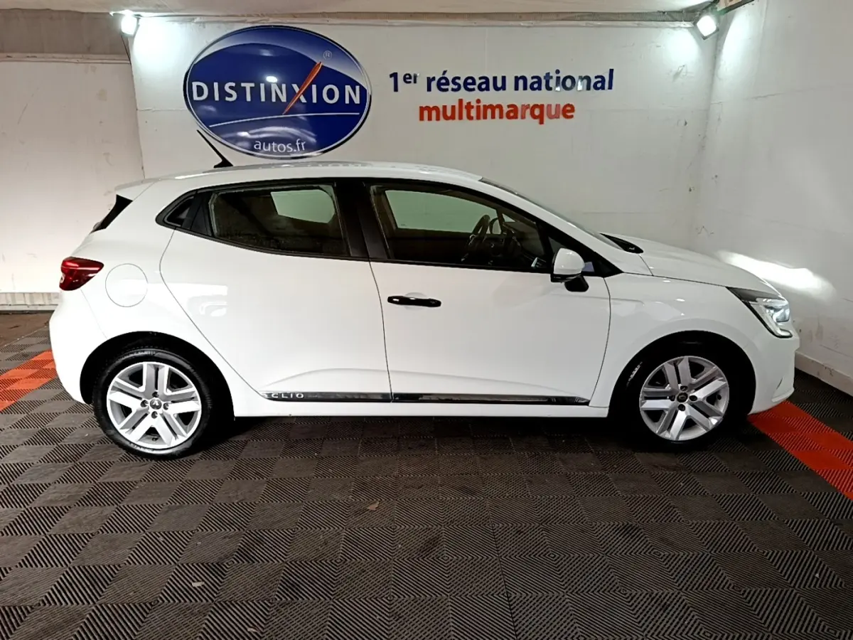 Profil droit d'une Renault Clio Business blanche 2021, avec jantes alliage et logo Distinxion en arrière-plan.
