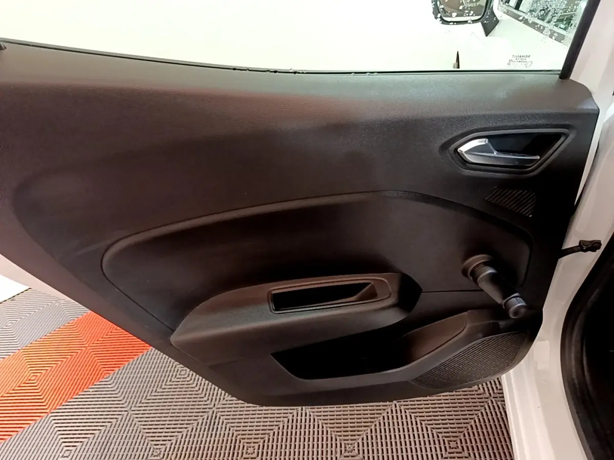 Vue rapprochée de la porte intérieure côté gauche noire d’une Renault Clio Business blanche, avec poignée de fenêtre manuelle.