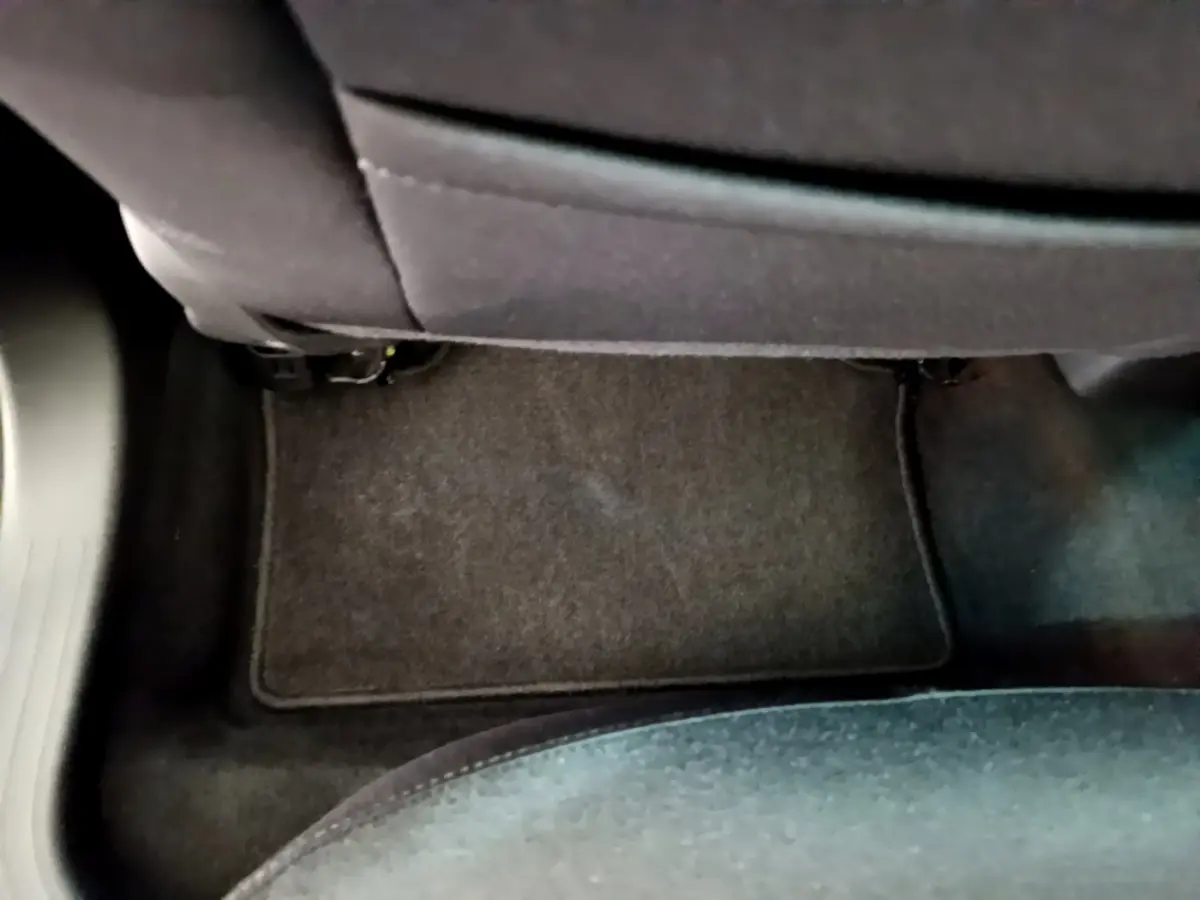 Vue rapprochée du tapis de sol noir sous le siège arrière d'une Renault Clio Business blanche de 2021.