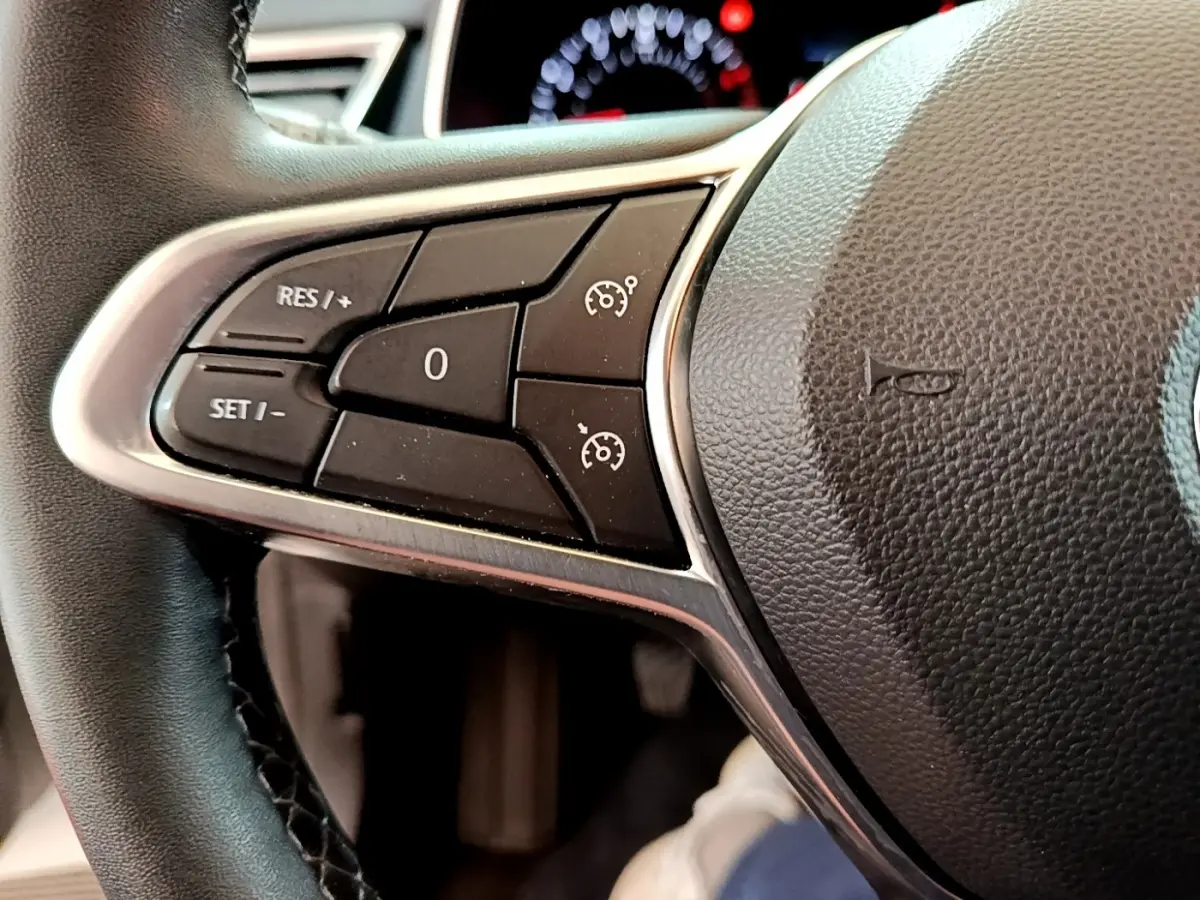 Gros plan sur les commandes du régulateur de vitesse au volant cuir noir de la Renault Clio Business blanche 2021.