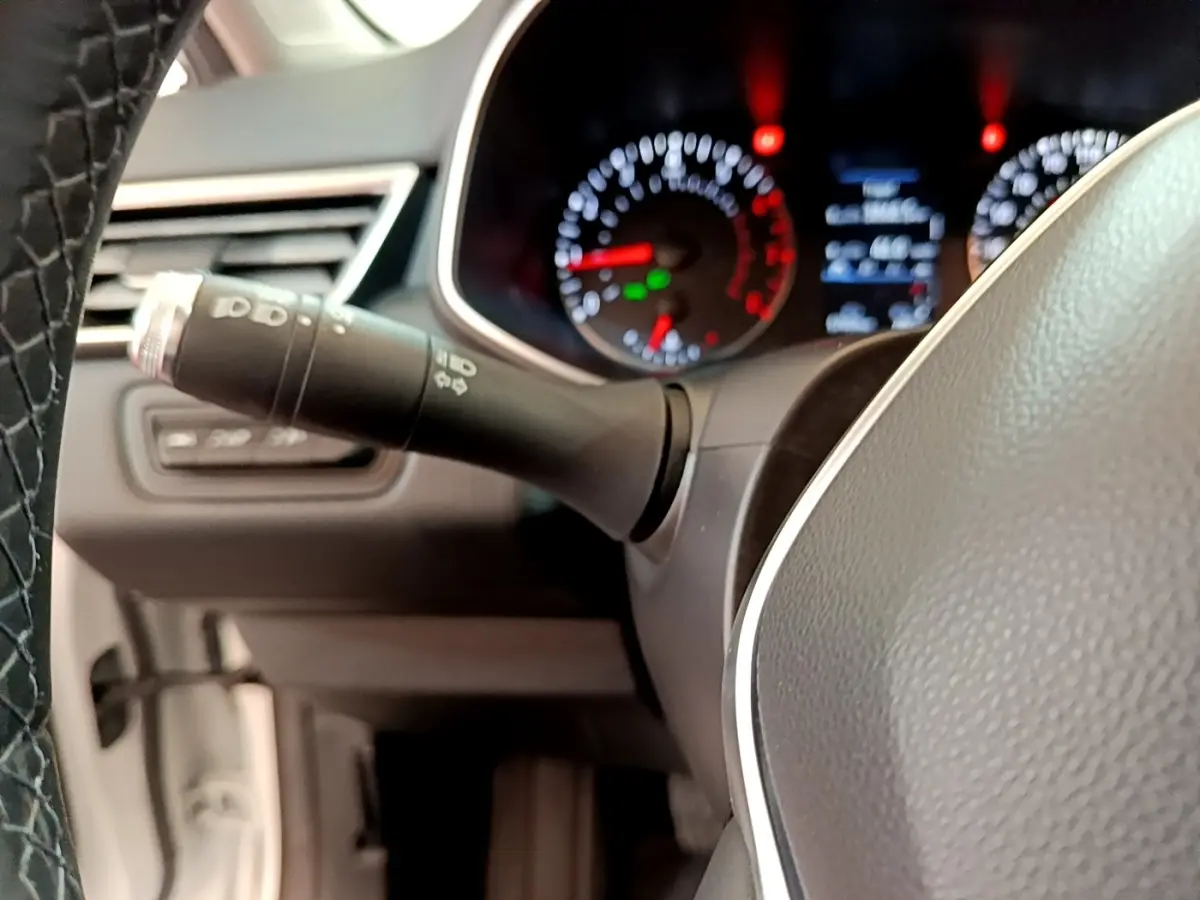 Gros plan sur le volant et le combiné d'instruments éclairé de la Renault Clio Business blanche de 2021.