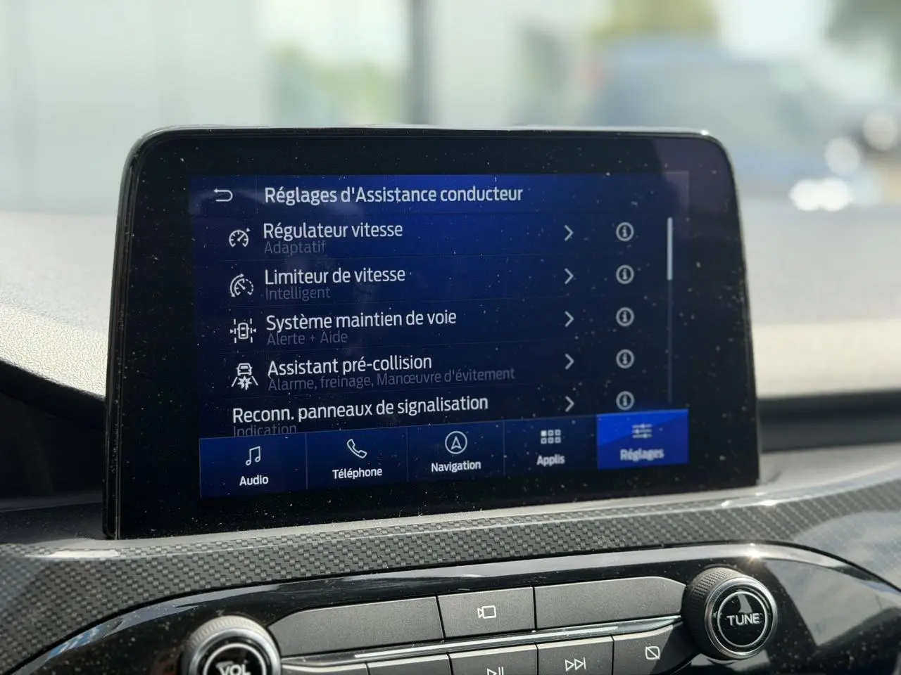 Écran tactile central du Ford Kuga 2024 affichant les réglages d’assistance conducteur, intérieur gris clair.