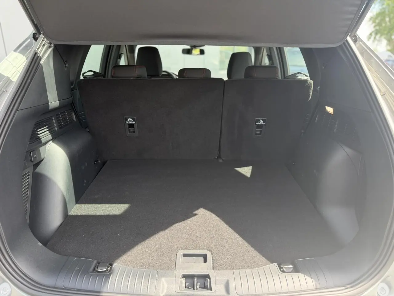 Coffre ouvert vu de l'arrière du Ford Kuga gris Solar, montrant l'espace de chargement et les dossiers arrière noirs.
