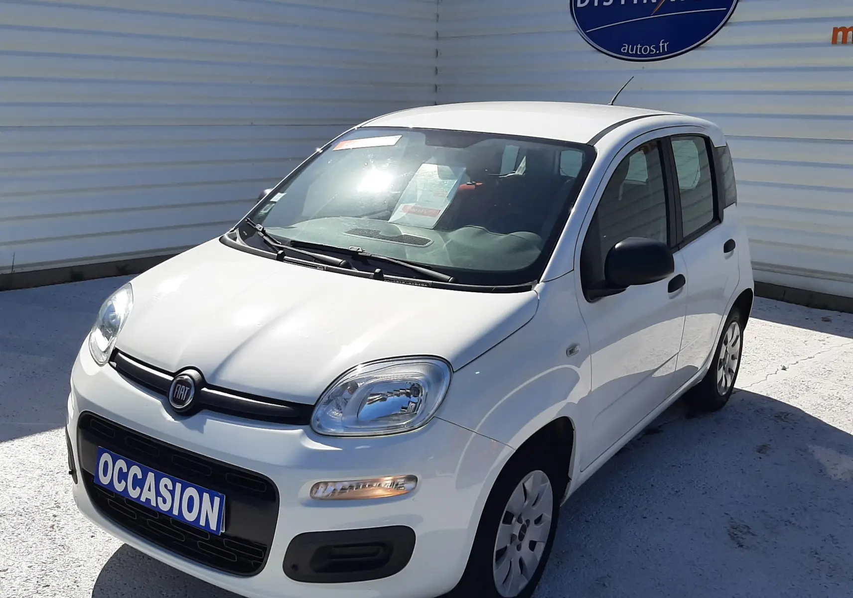 Vue 3/4 avant droite d'une Fiat Panda blanche 2018 avec plaque "OCCASION" sur un parking extérieur.