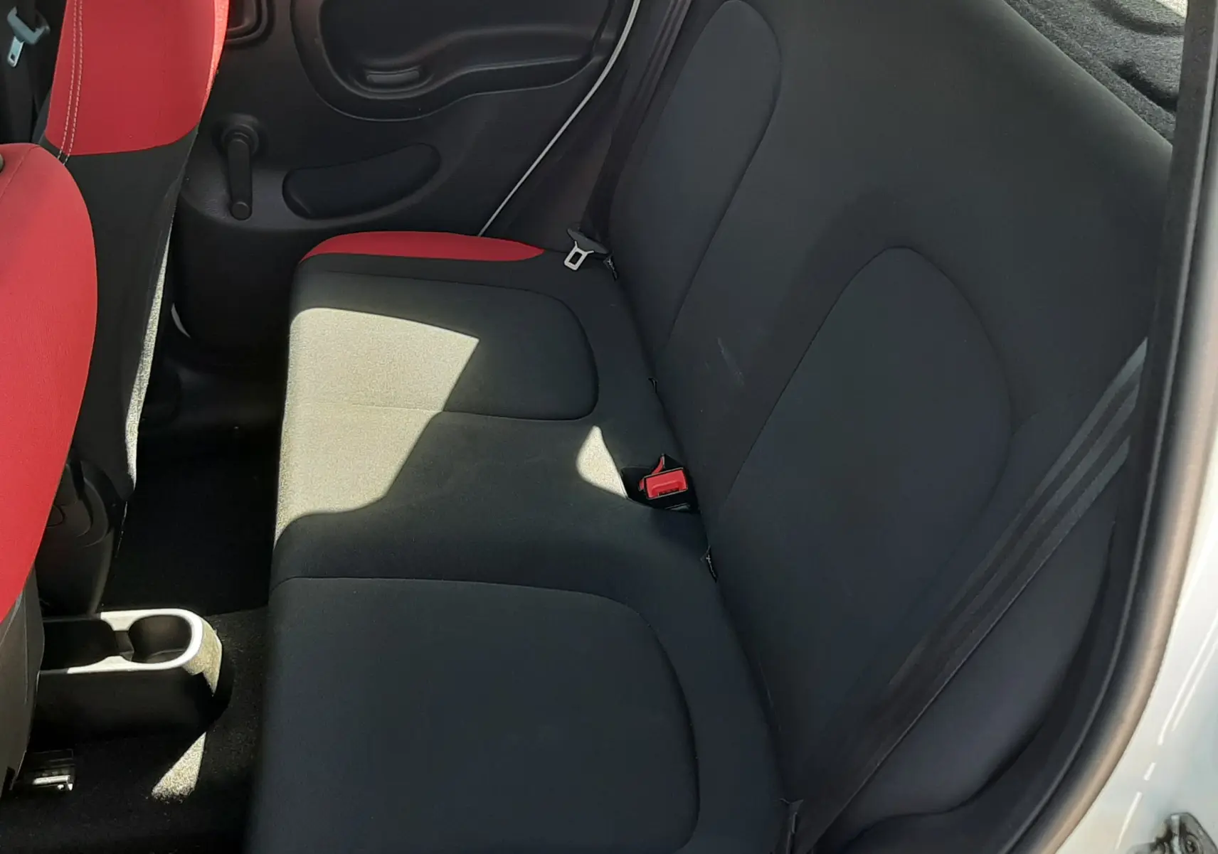 Rétroviseur côté gauche d'une Fiat Panda blanche 2018, avec vue sur une voiture rouge en arrière-plan.