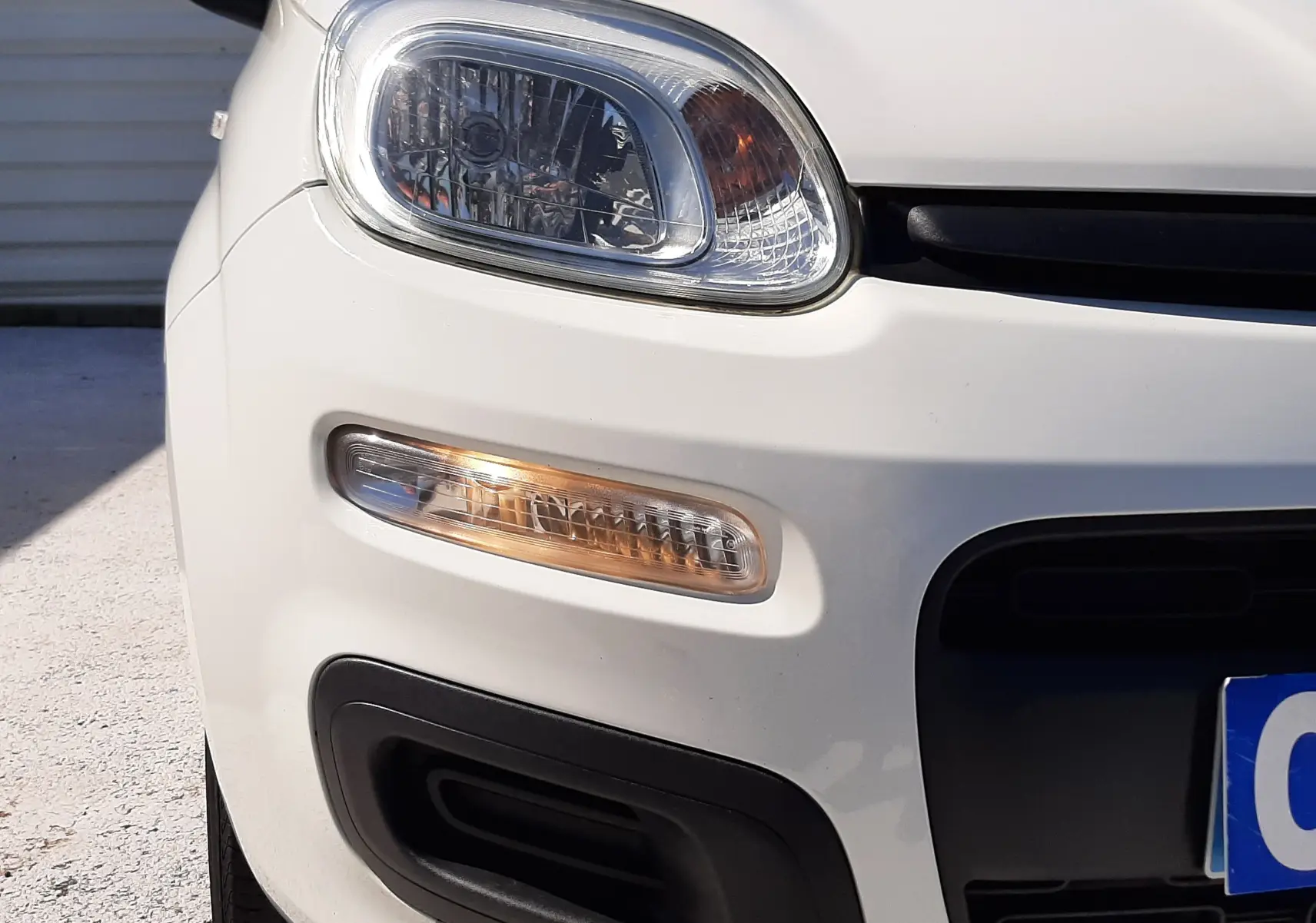 Vue de côté droit avant d'une Fiat Panda blanche 2018, mettant en valeur les vitres teintées et les poignées noires.