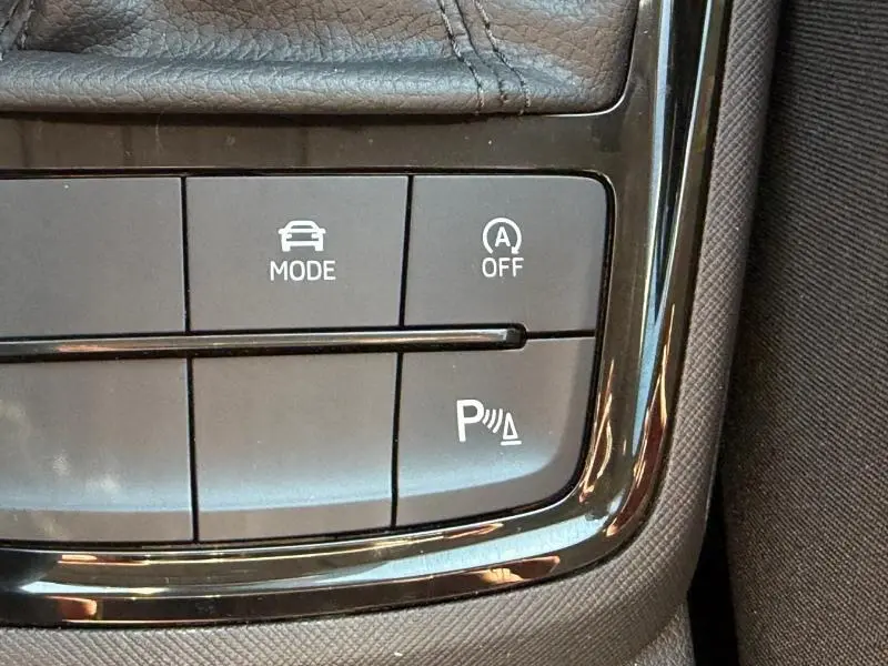 Gros plan sur les boutons de commande noirs brillants du tableau de bord d'une Skoda Scala noir Magic nacré.