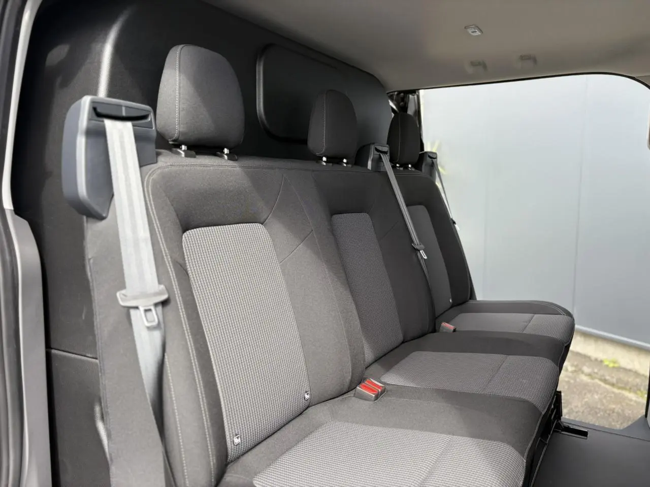 Vue intérieure côté droit montrant la banquette arrière en tissu rayé gris du Volkswagen Transporter T7 ProCab 2026.