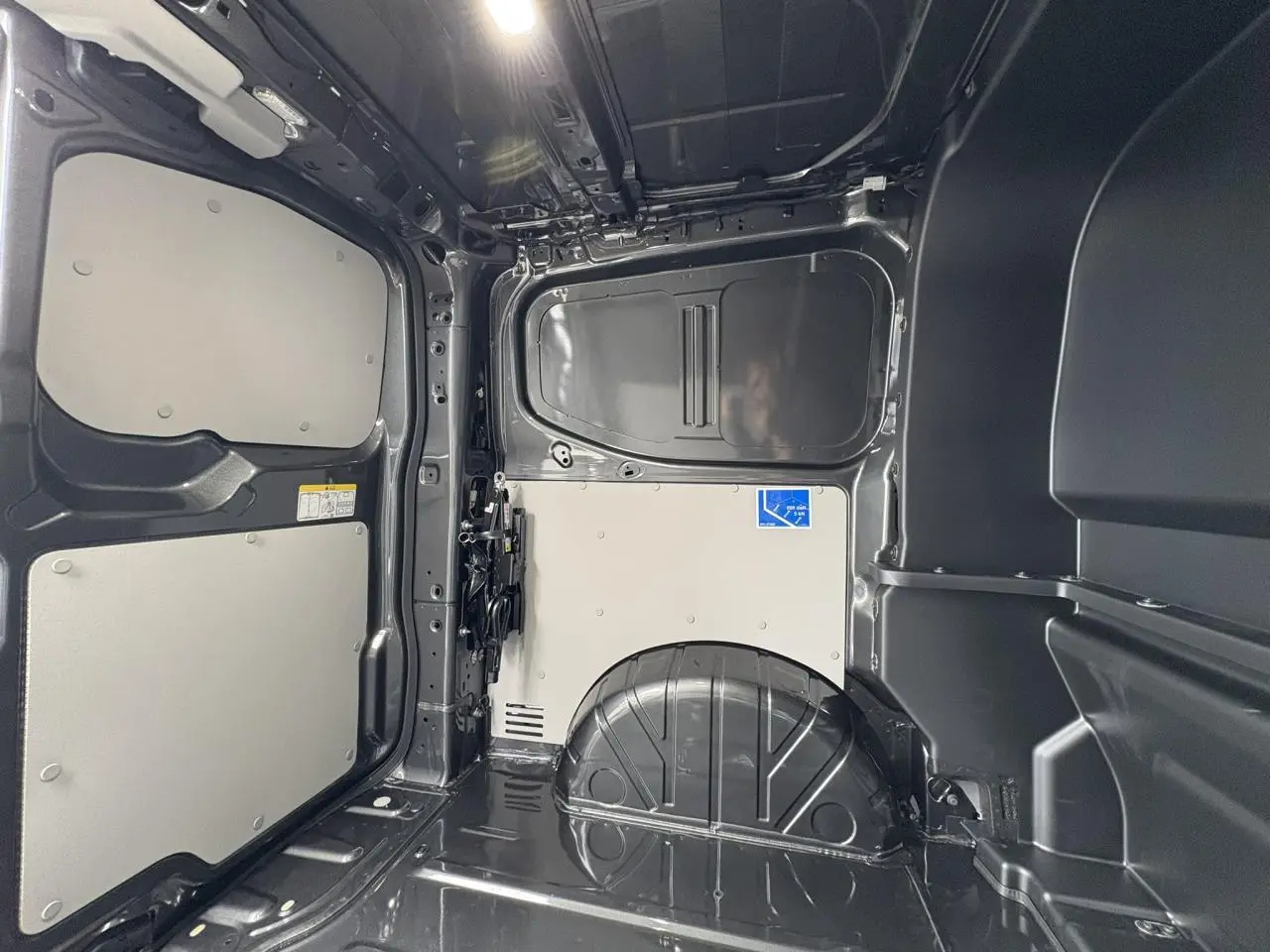 Vue intérieure de la zone de chargement du Volkswagen Transporter T7 ProCab graphite métallisé, montrant les parois et plancher métalliques.